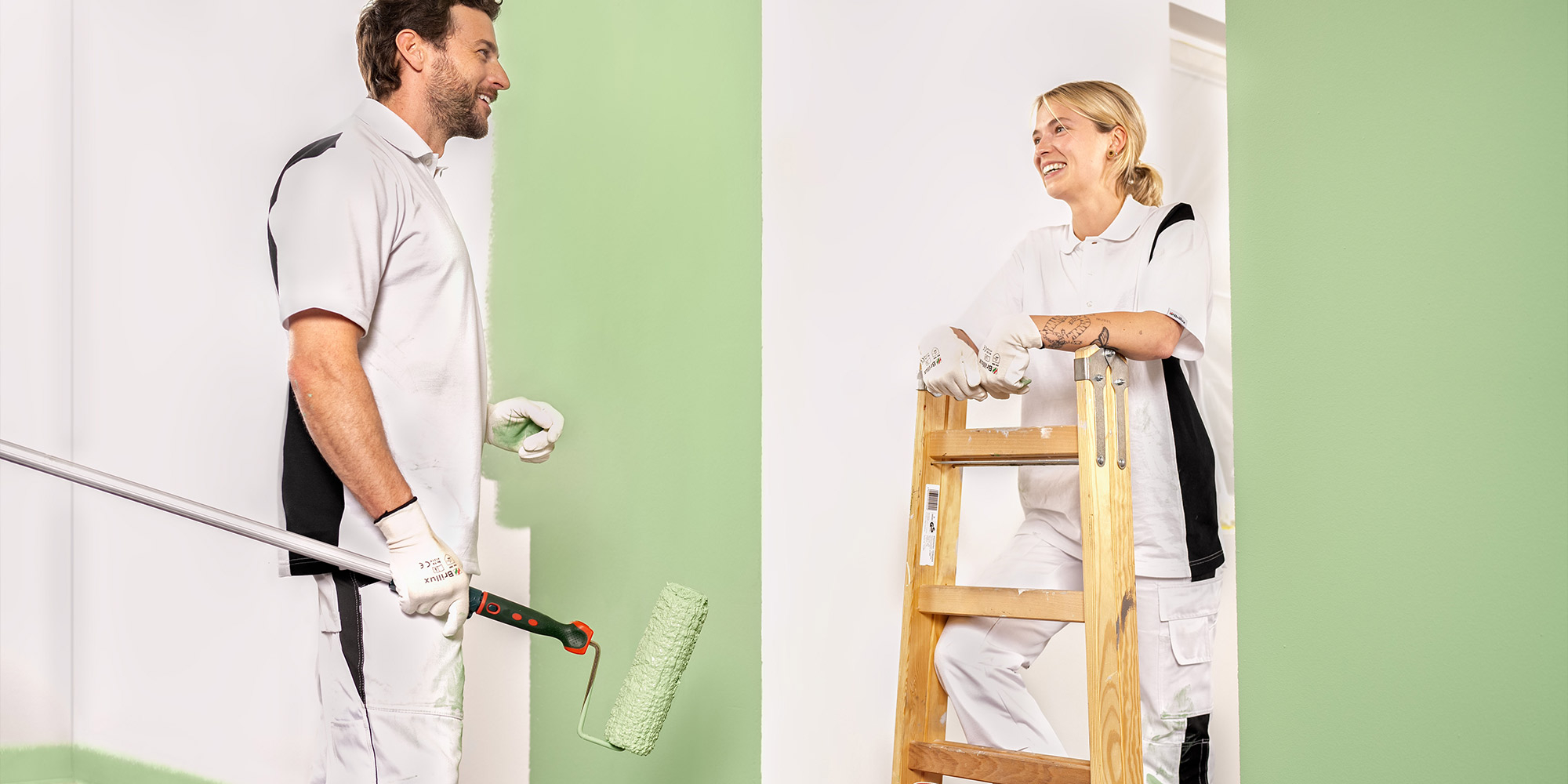 Farbrolle trägt weiße Beschichtung auf strukturierte Fassade auf, gleichmäßiger Außenanstrich