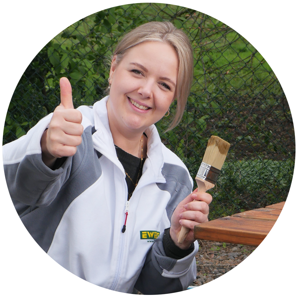 Portrait einer Malerin mit Pinsel, Daumen hoch - Profi Tipp für den Anstrich von Außenholz