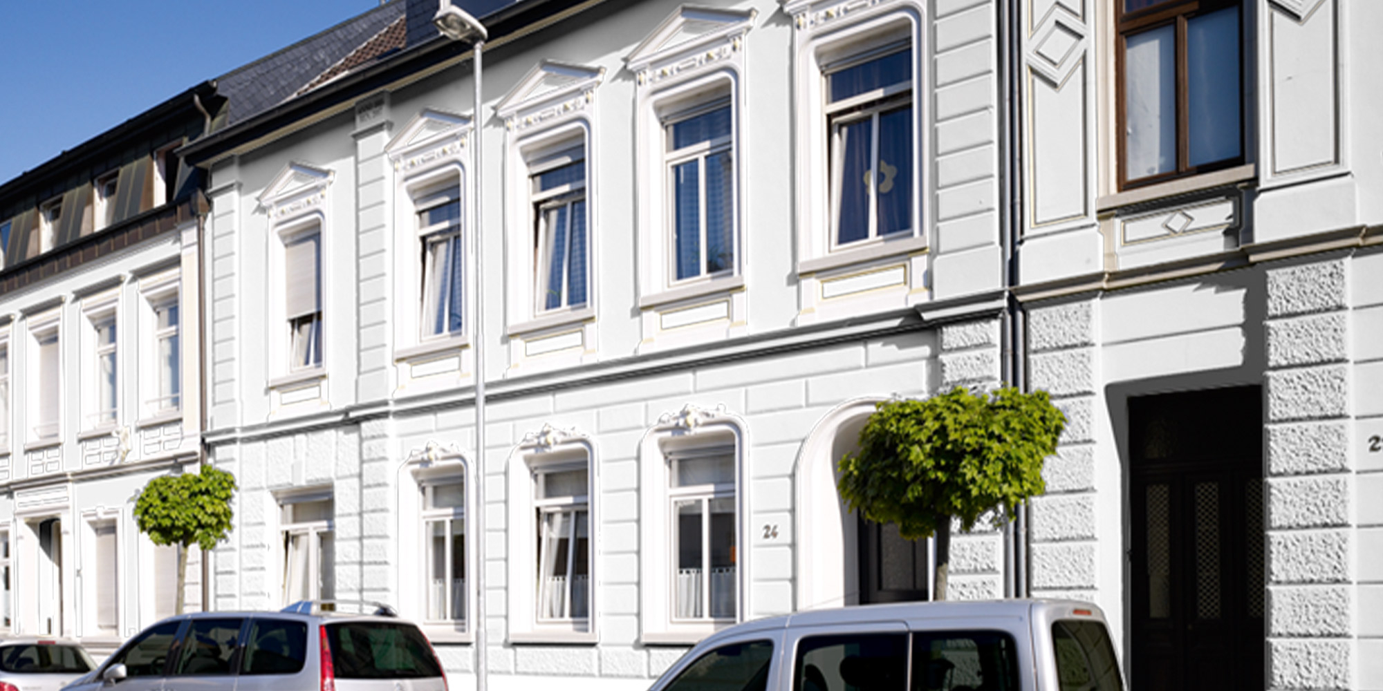 Weiße Altbaufassade in der Straßenansicht als Beispiel für streichbaren Füller