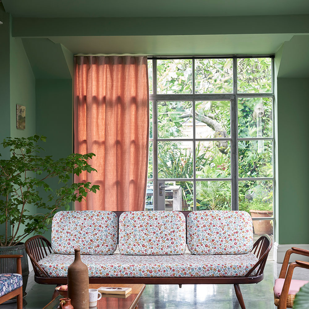 Wohnzimmer mit grün gestrichener Wand, großem Fenster und Sofa - Beispiel für Wunschfarbton