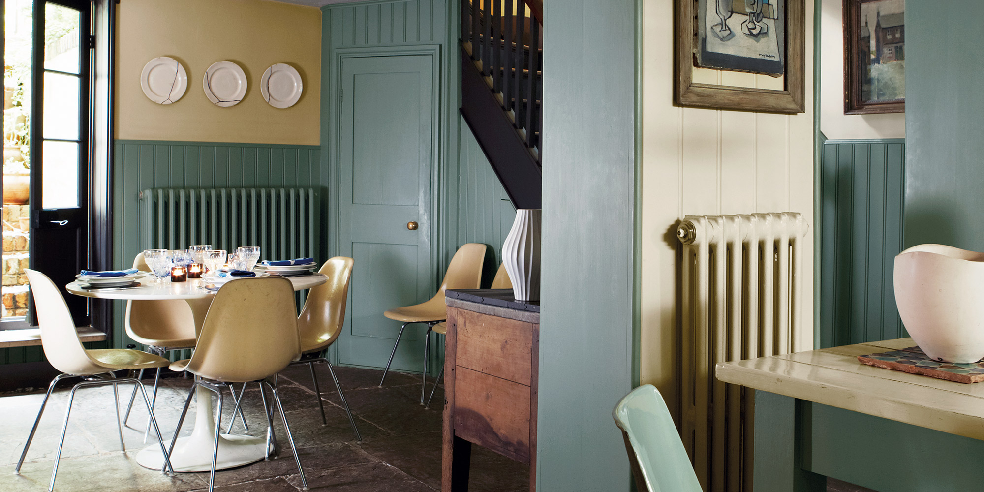Essbereich mit gedeckten Tisch, grüner Wandvertäfelung und Heizkörper an der Wand