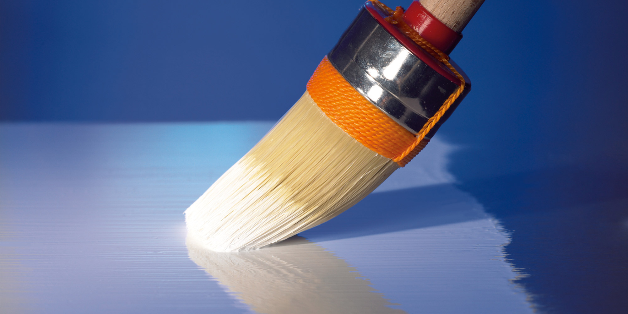Pinsel trägt hellen Lack auf eine glänzende blaue Oberfläche auf