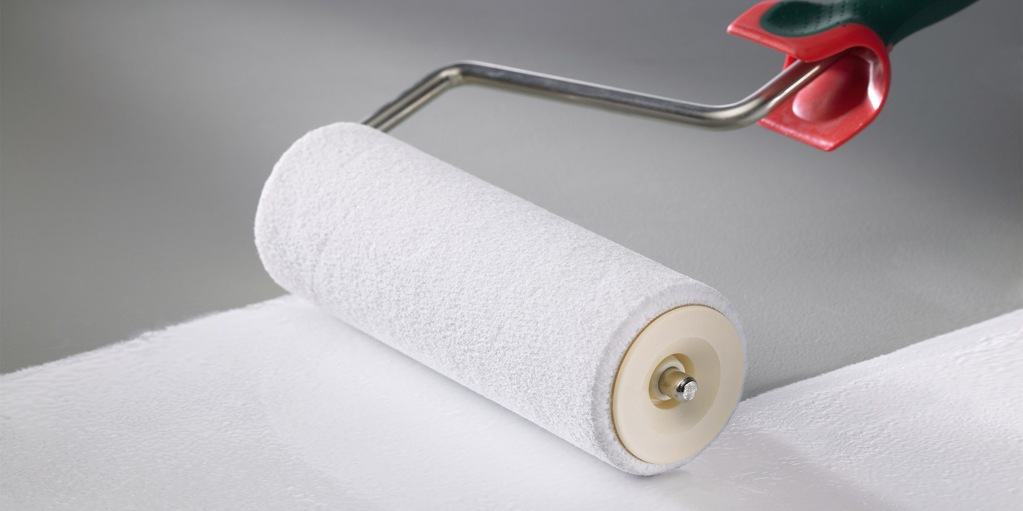 Farbwalze trägt weiße Farbe auf eine Fläche auf