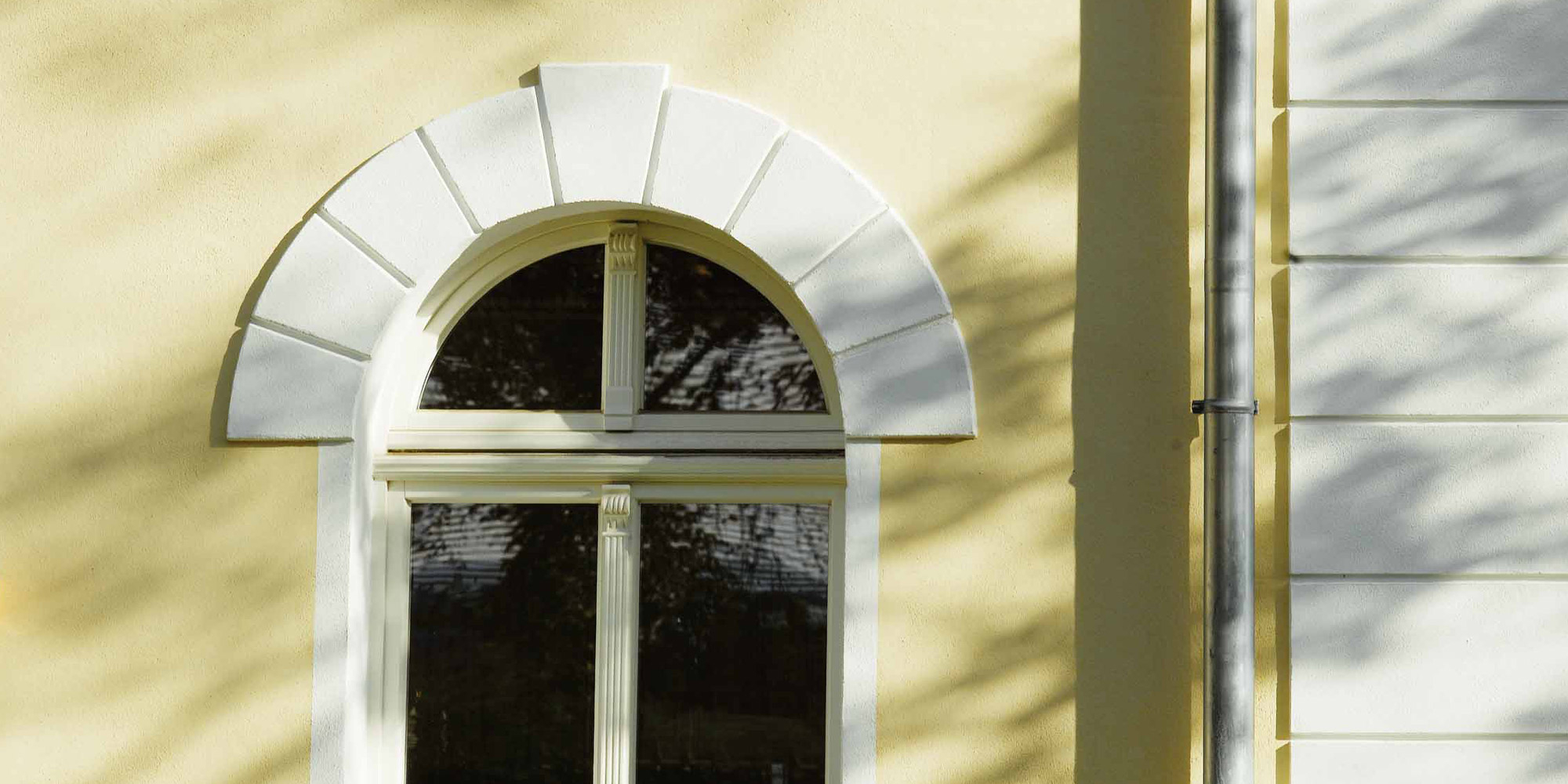 Rundbogenfenster mit dekorativer Stuckrahmung