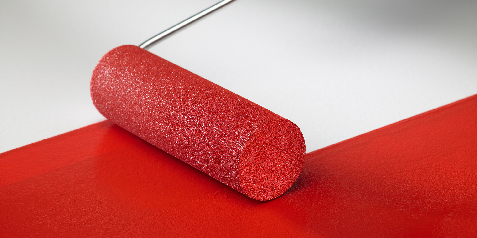 Roter Sikkens Farbroller verteilt Farbe auf einer weißen Oberfläche