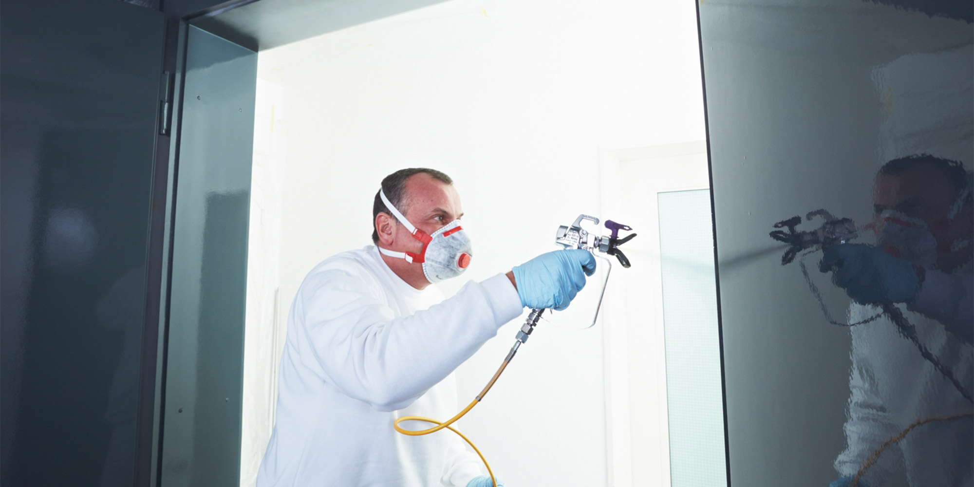 Lackierarbeiten mit Spritzpistole, feiner Auftrag auf dunkler Oberfläche im Innenraum