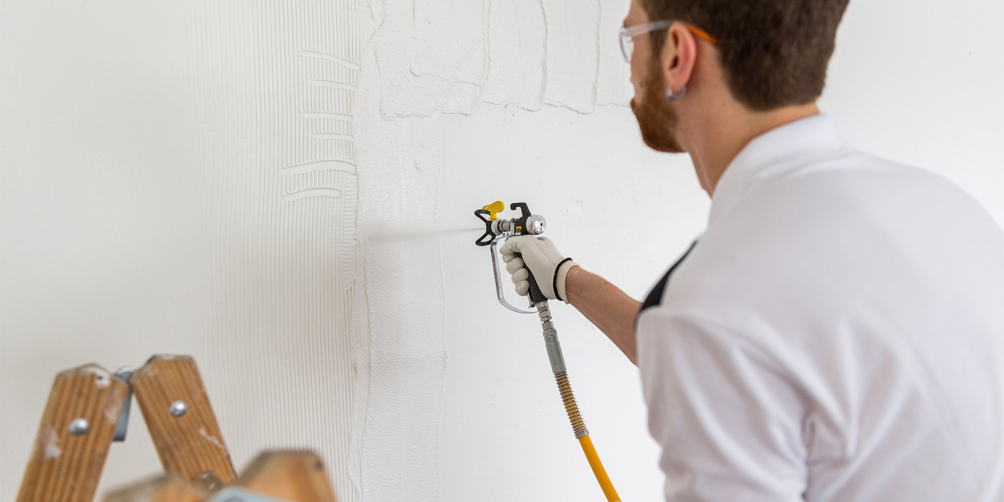 Handwerker spritzt Spachtelmasse auf die Wand für eine glatte Oberfläche
