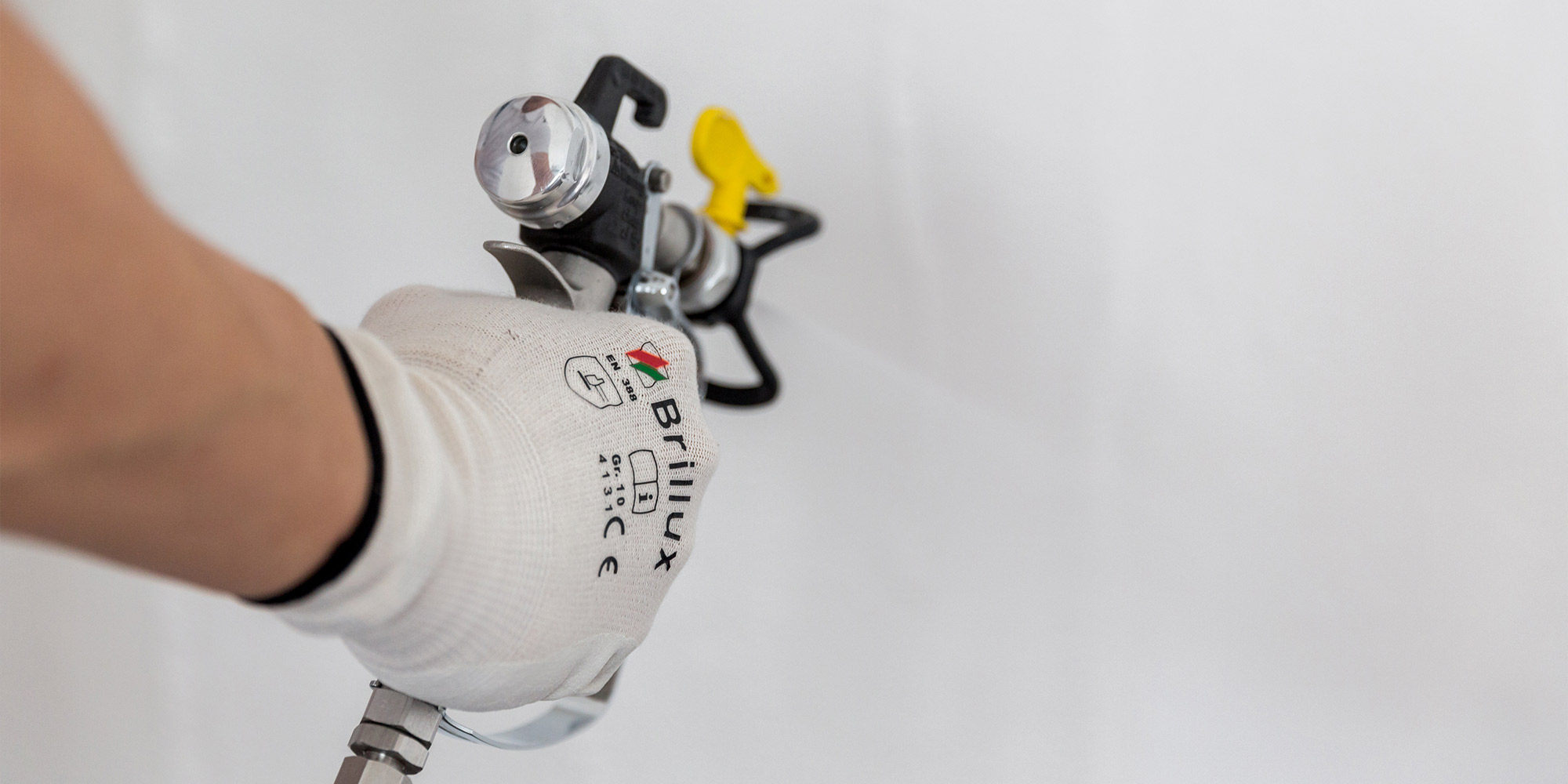 Spritzgerät trägt weiße Spachtelmasse gleichmäßig auf eine Wand auf