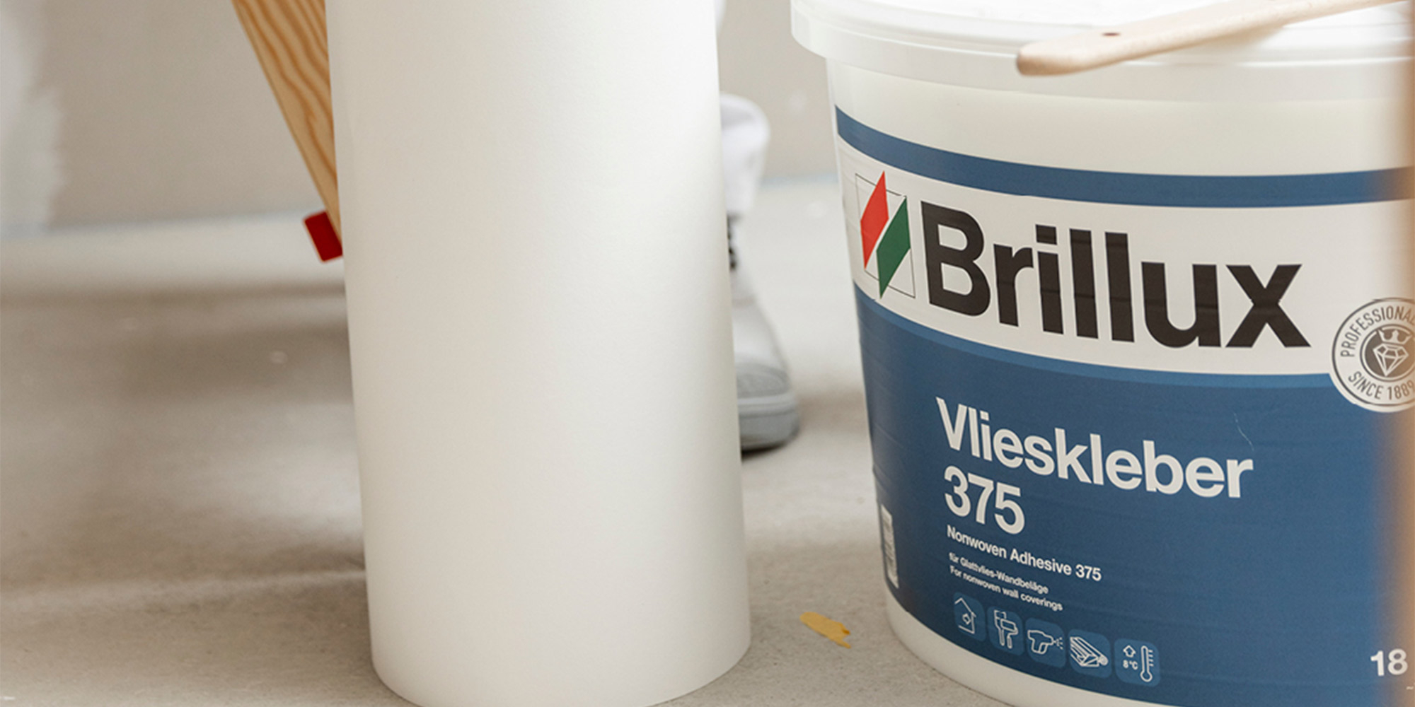 Eimer Brillux Vlieskleber 375 neben Tapetenrolle, Kleber für Glattvlies Verarbeitung