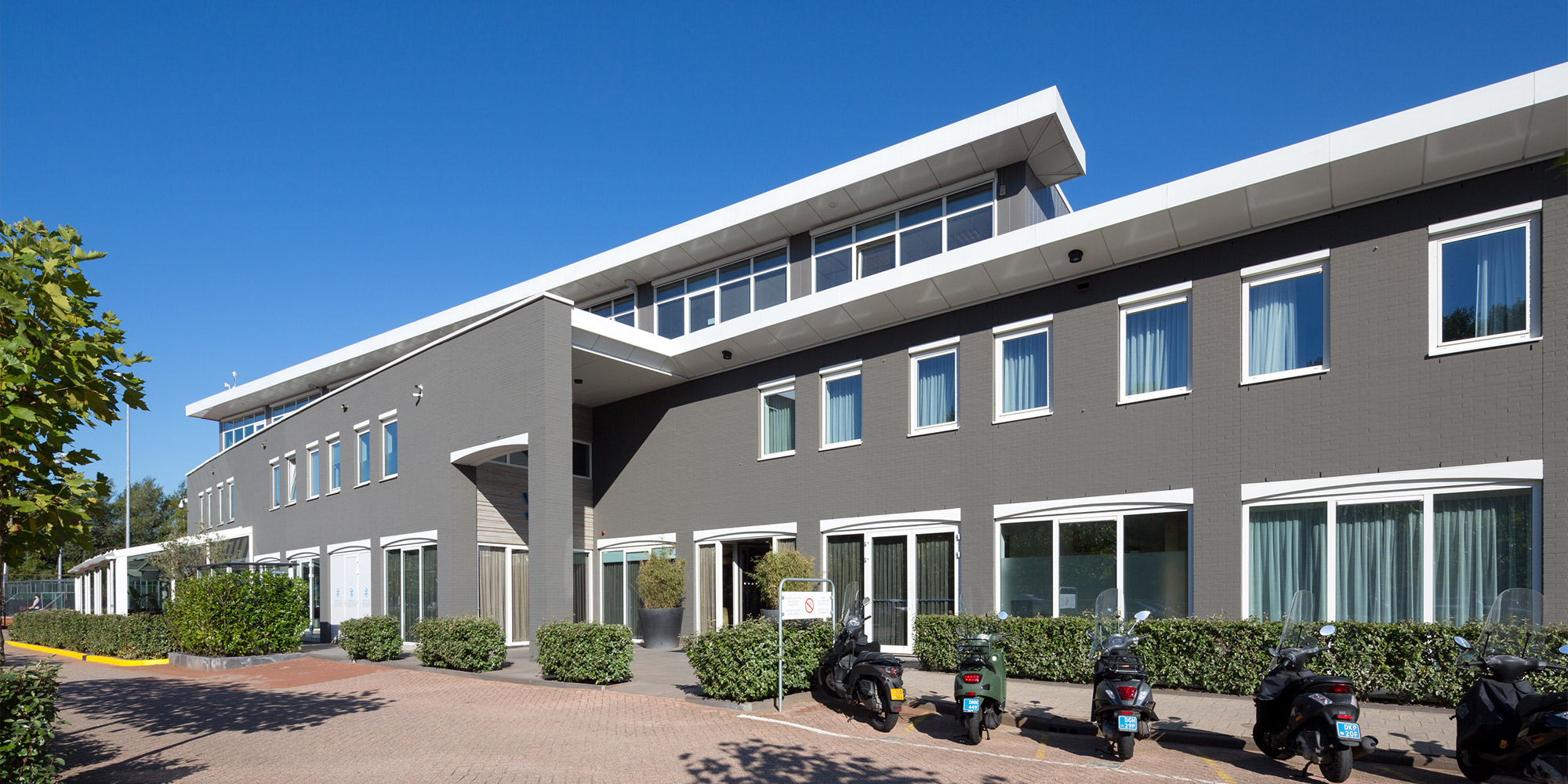 Modernes Gebäude mit grauer Fassade und weißen Fensterrahmen im Sonnenschein