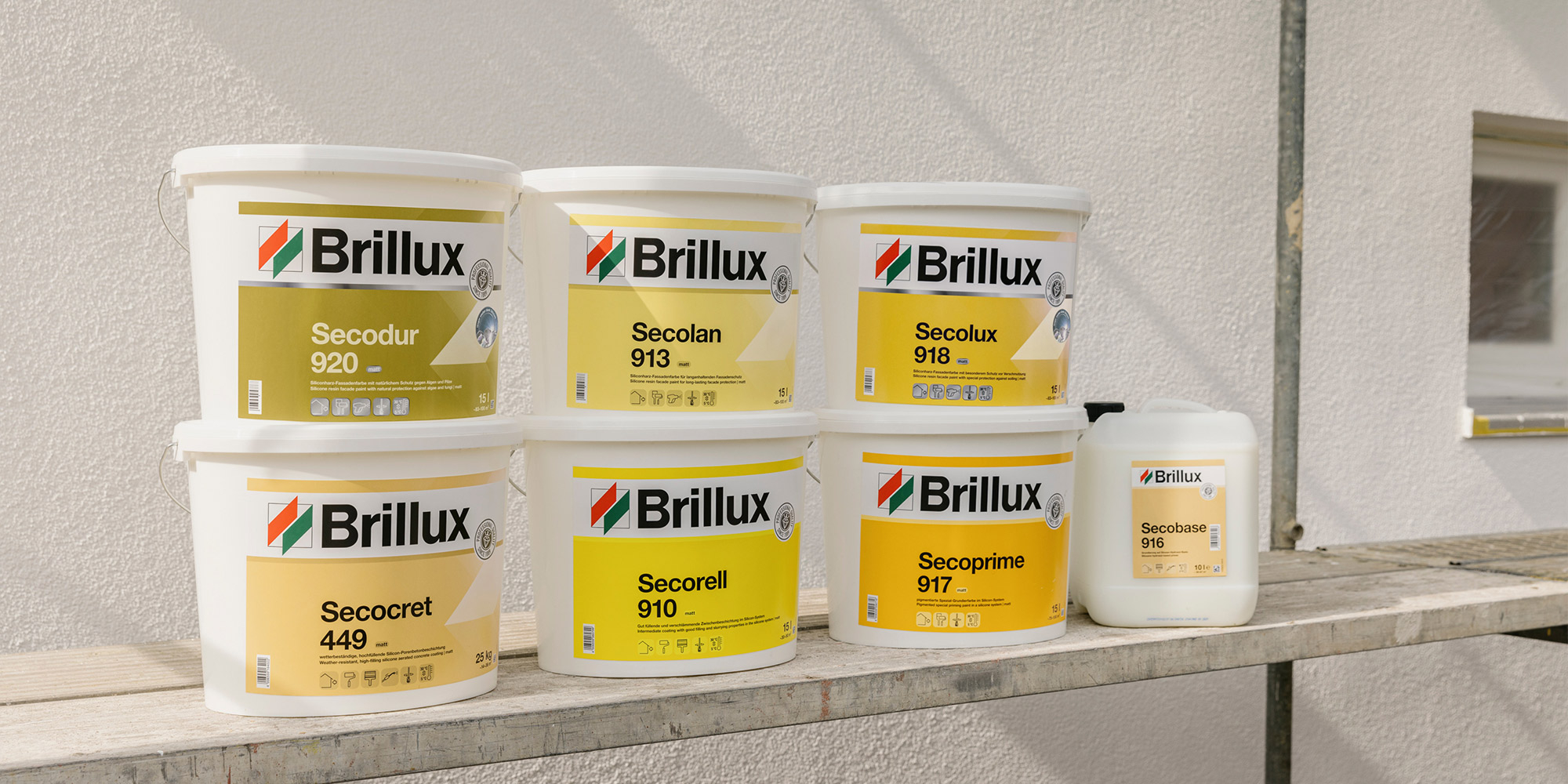 Brillux Silicon-Fassadenfarben und passende Produkte in Eimern auf Gerüstbrett vor Außenwand