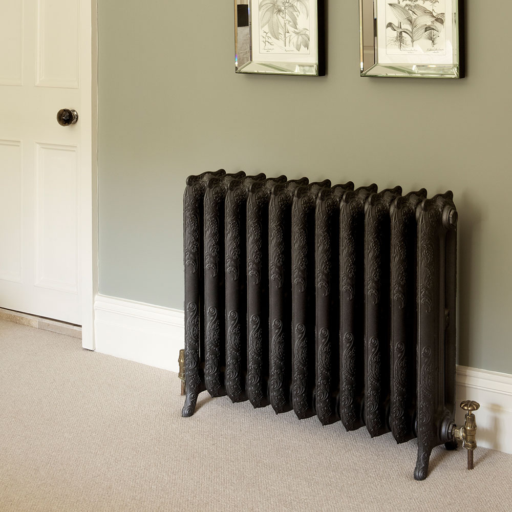 Dunkler Gussheizkoerper an gruener Wand im Wohnraum - Ergebnisbeispiel nach dem Heizkoerper streichen