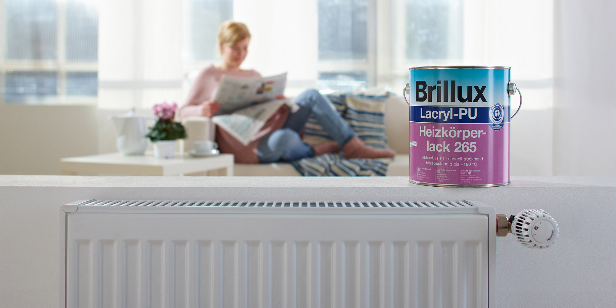 Dose Brillux Heizkörperlack 265 steht auf einem Heizkörper, Wohnraum im Hintergrund