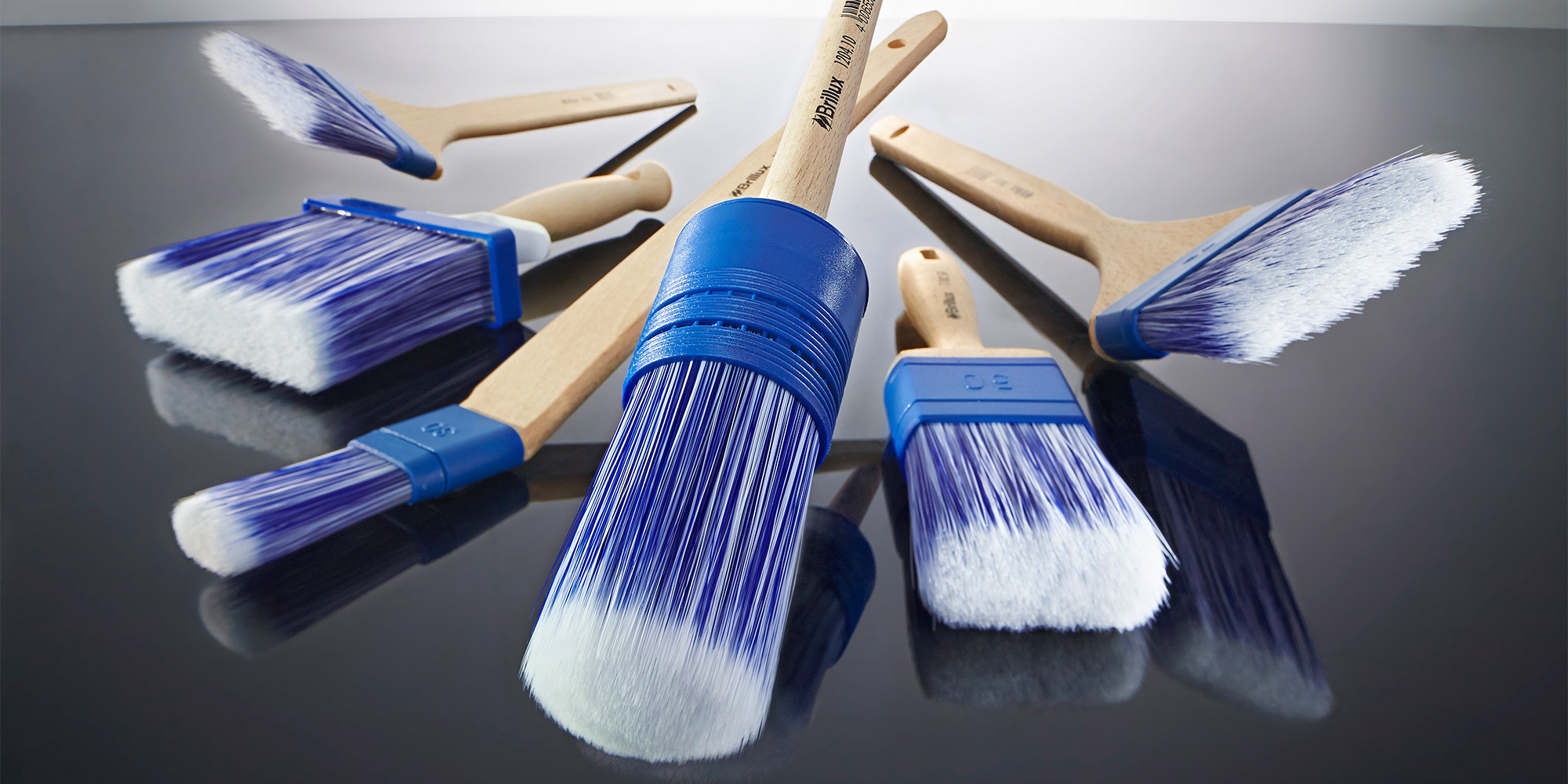Mehrere Malerpinsel mit blauen Borsten auf einer glatten Flaeche