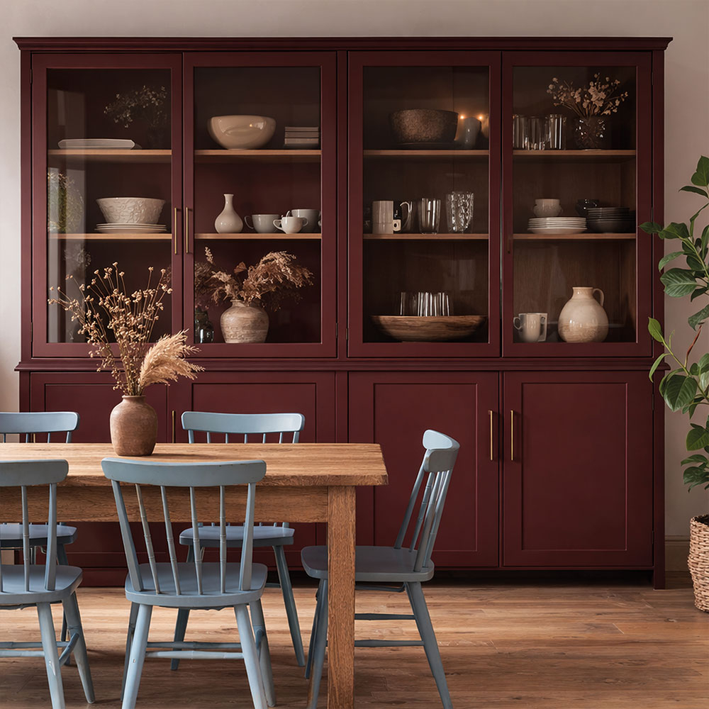 Dunkelbraun gestrichener Wohnzimmerschrank mit geöffneten Gittertüren und rosafarbenen Regalböden am Esstisch