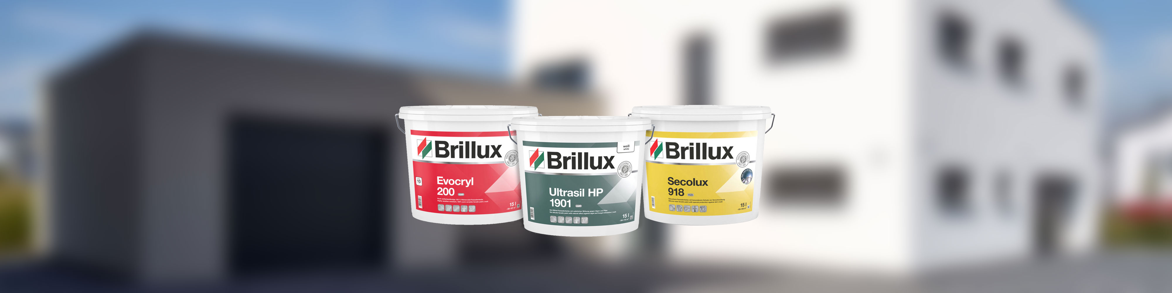 Drei Brillux Farbeimer fuer Fassadenanstrich vor unscharfem Haus - Evocryl 200, Ultrasil HP 1901 und Secolux 918