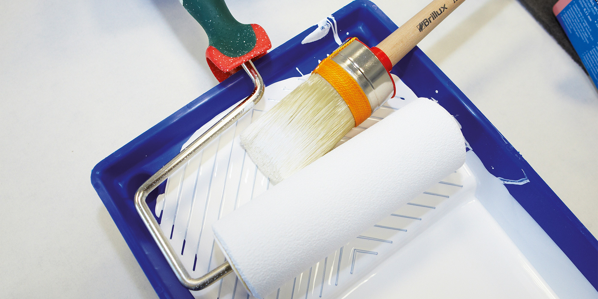 Farbwanne mit Rolle und Pinsel fuer gleichmaessigen Auftrag bei Beschichtungen