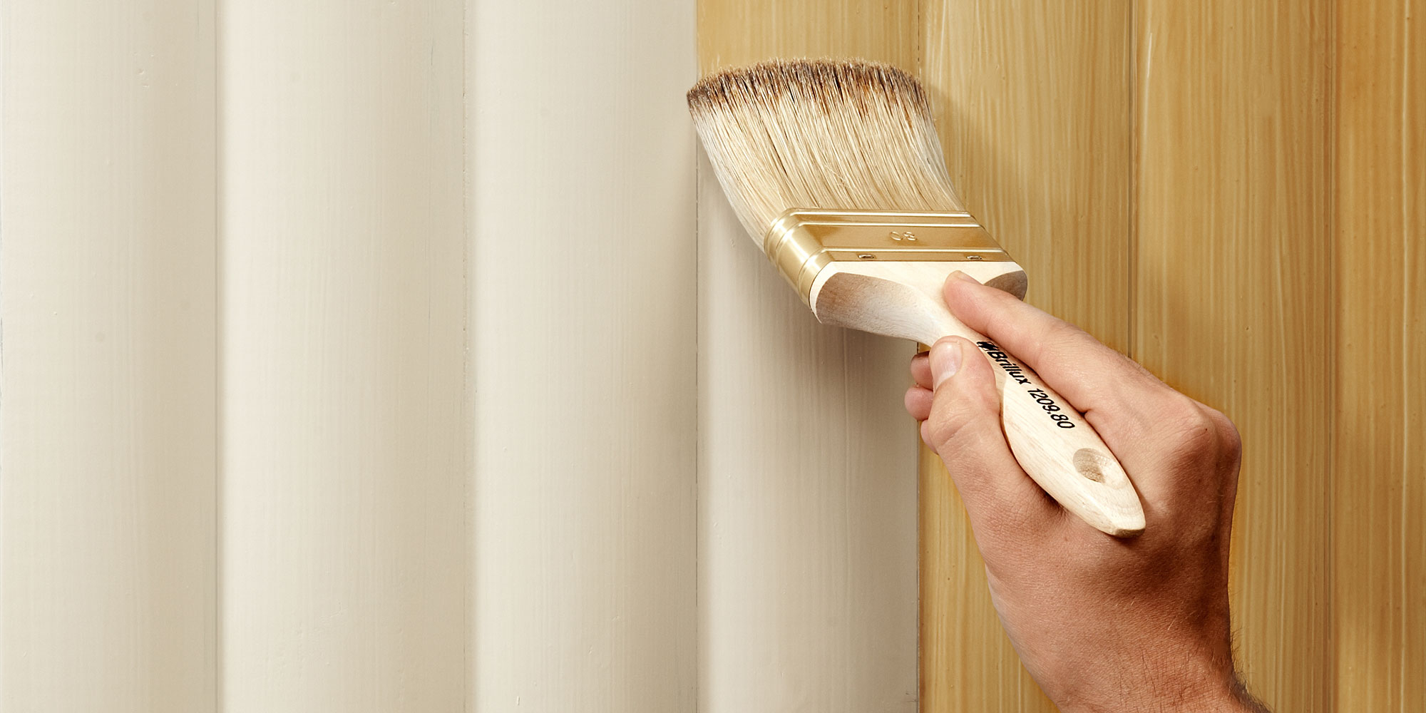 Hand trägt mit Pinsel eine Aufhelltechnik auf helles Holz auf, um die Oberfläche aufzuhellen