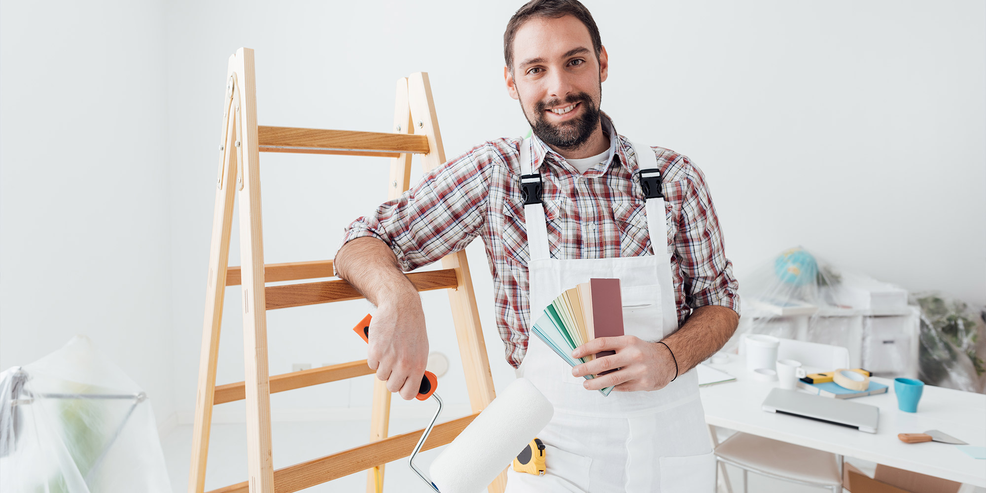 Maler mit Farbkarte und Lackrolle vor Leiter, Auswahl für Holz, Metall und Heizkörper