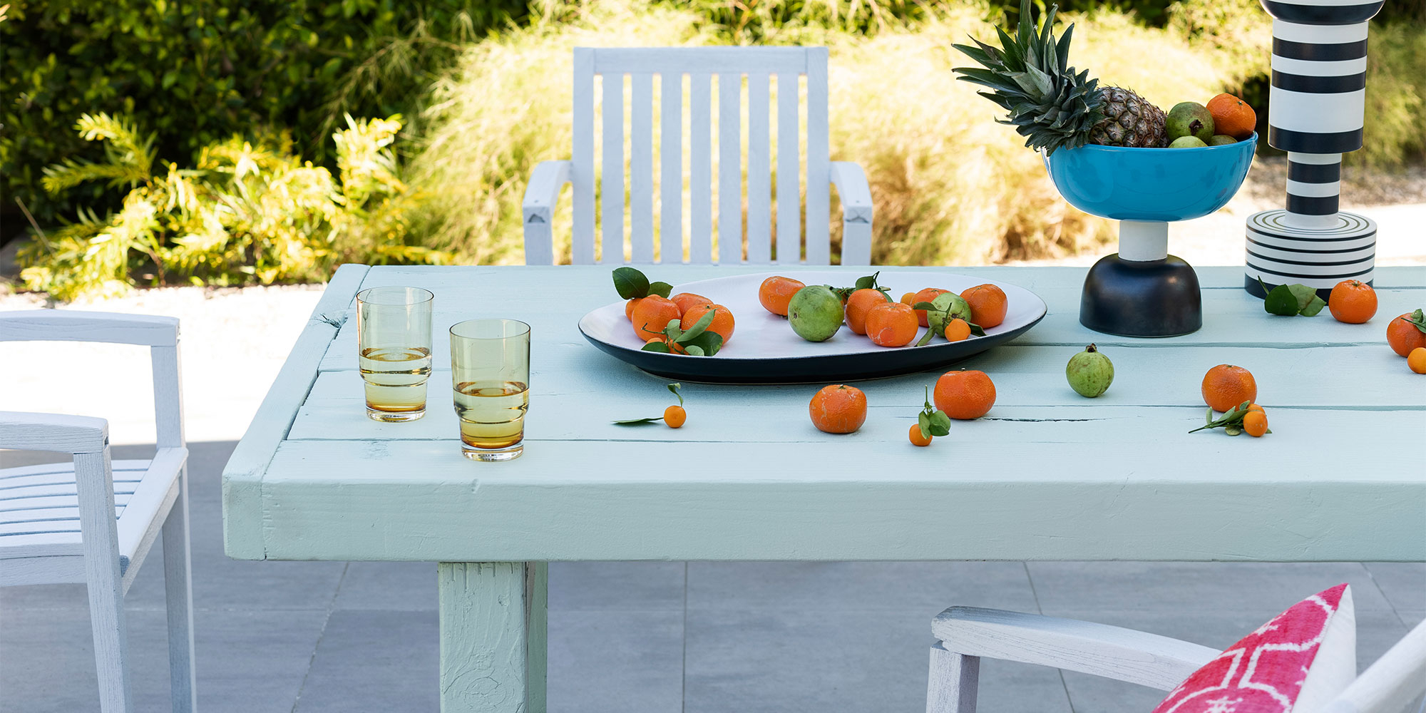 Hell gestrichener Gartentisch im Freien mit Obst und Gläsern - Beispiel für deckenden Außenanstrich