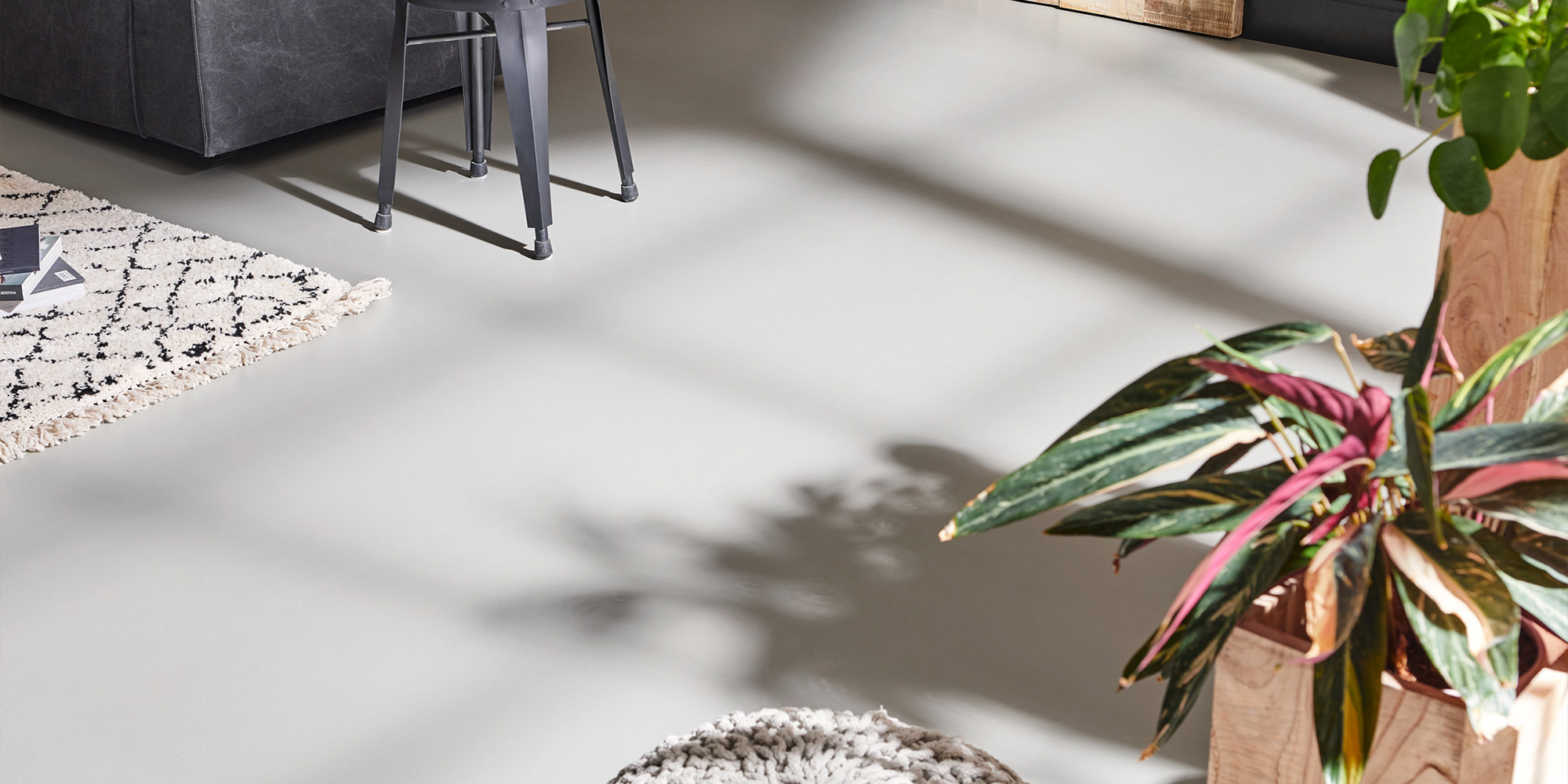 Heller grauer Boden mit Pflanzen und Teppich im Wohnbereich, Beispiel für Bodenbeschichtung
