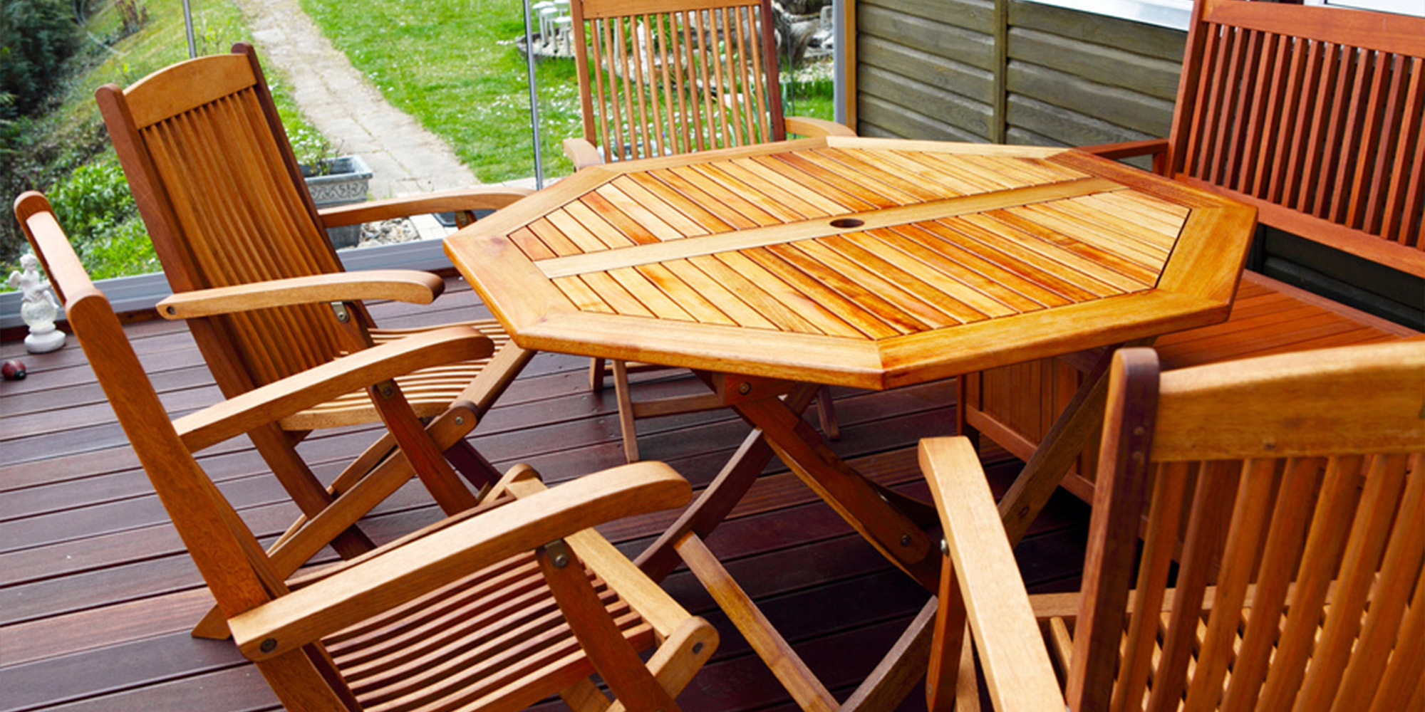 Gartenmöbel aus geöltem Holz auf einer Terrasse, bestehend aus achteckigem Tisch und mehreren Stühlen