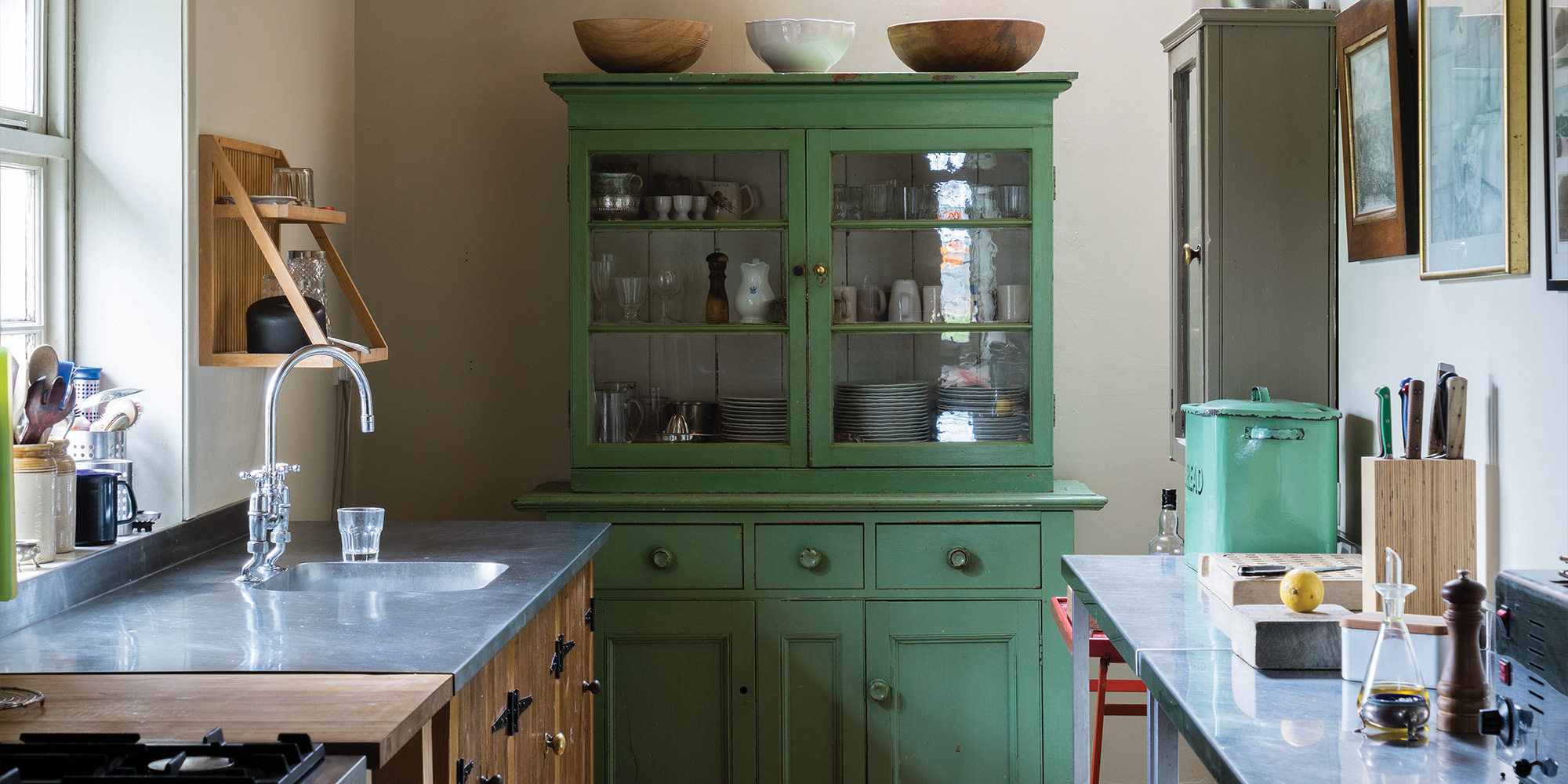 Küche mit Arbeitsplatte und grünem Geschirrschrank mit Glastüren