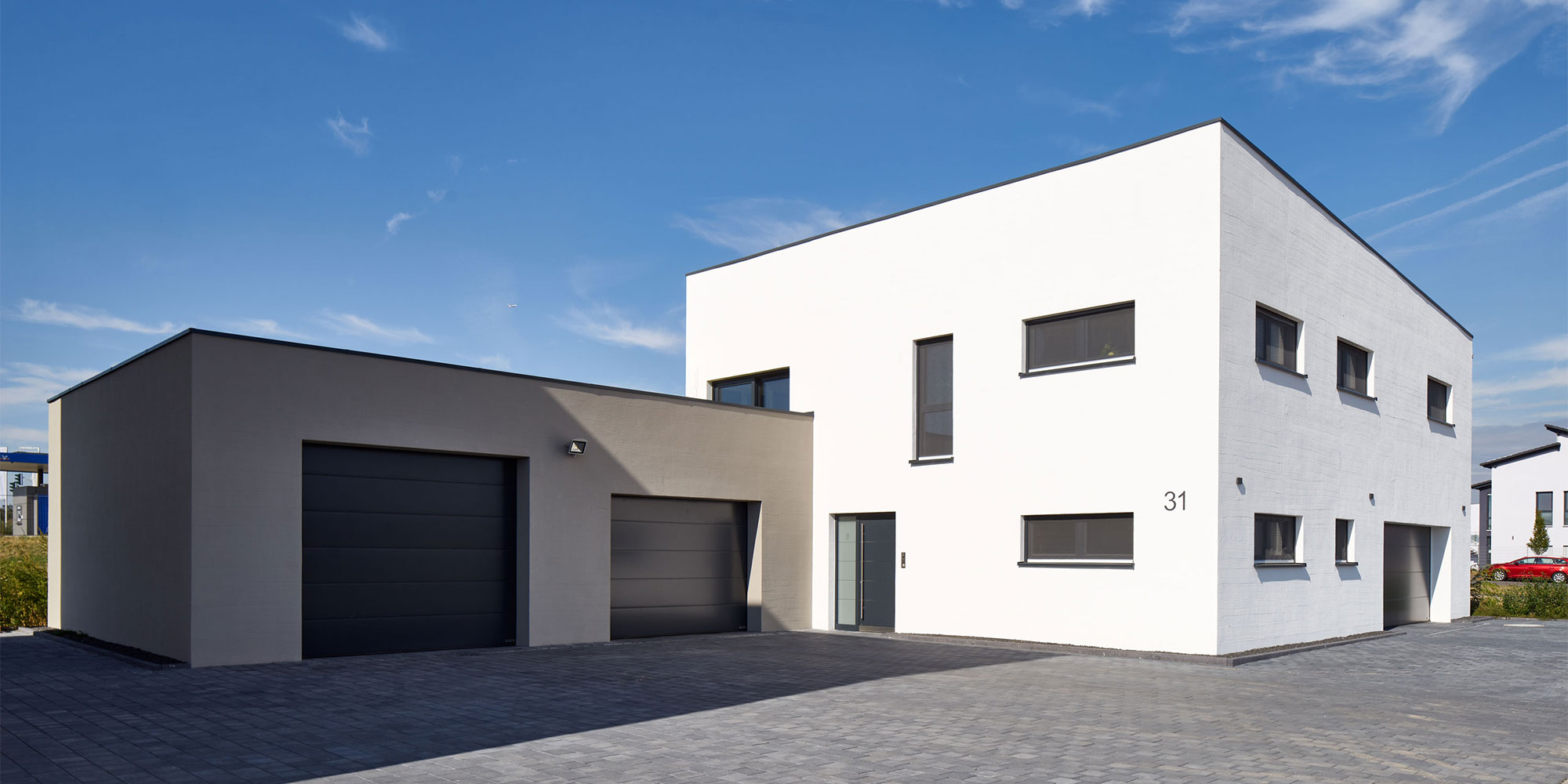 Modernes Haus mit heller Putzfassade und dunkler Garage als Beispiel für Außenputz