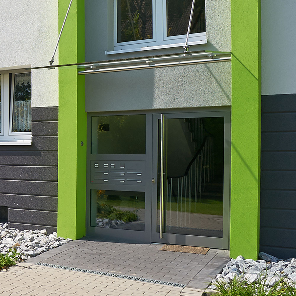 Moderne Eingangstür mit Glasflächen und dunklem Rahmen in grün grauer Fassade - Beispiel für Haustür Renovierung