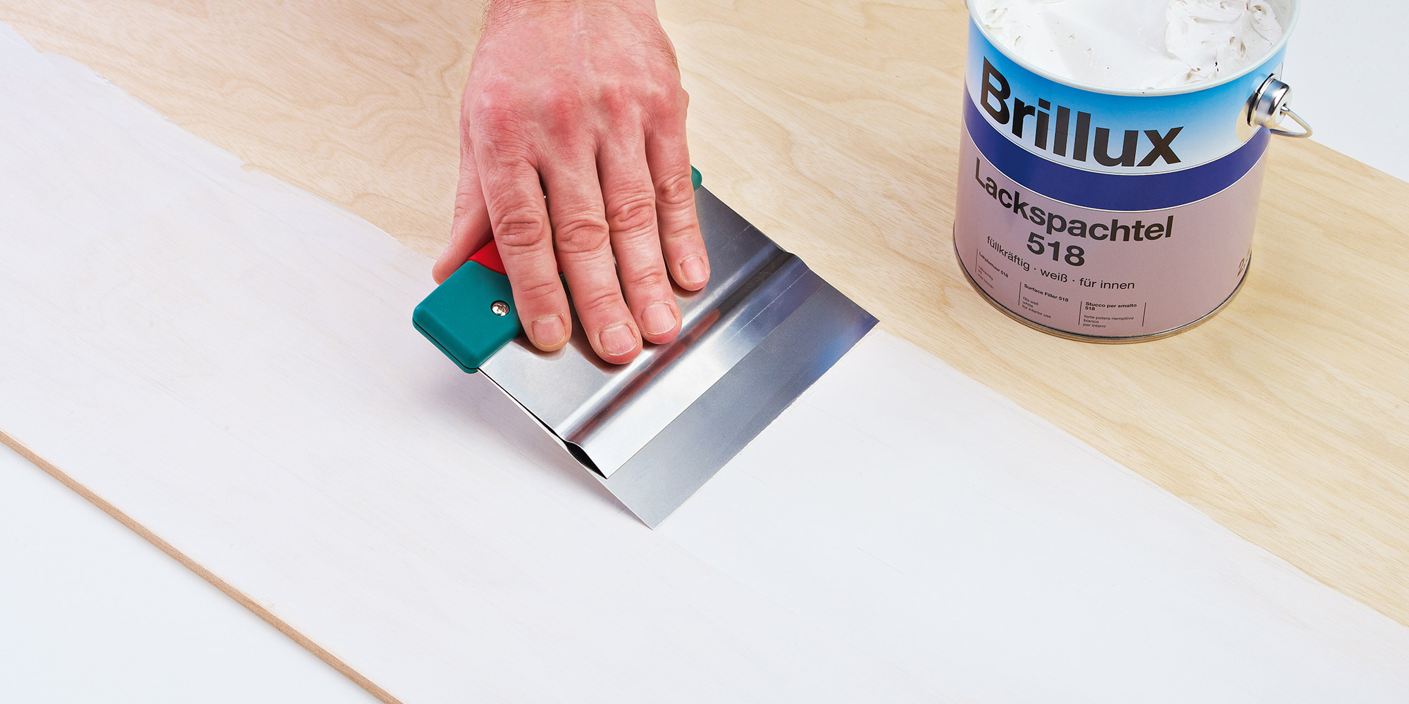 Hand glaettet Spachtelmasse mit einer Glattkelle auf einem Brett
