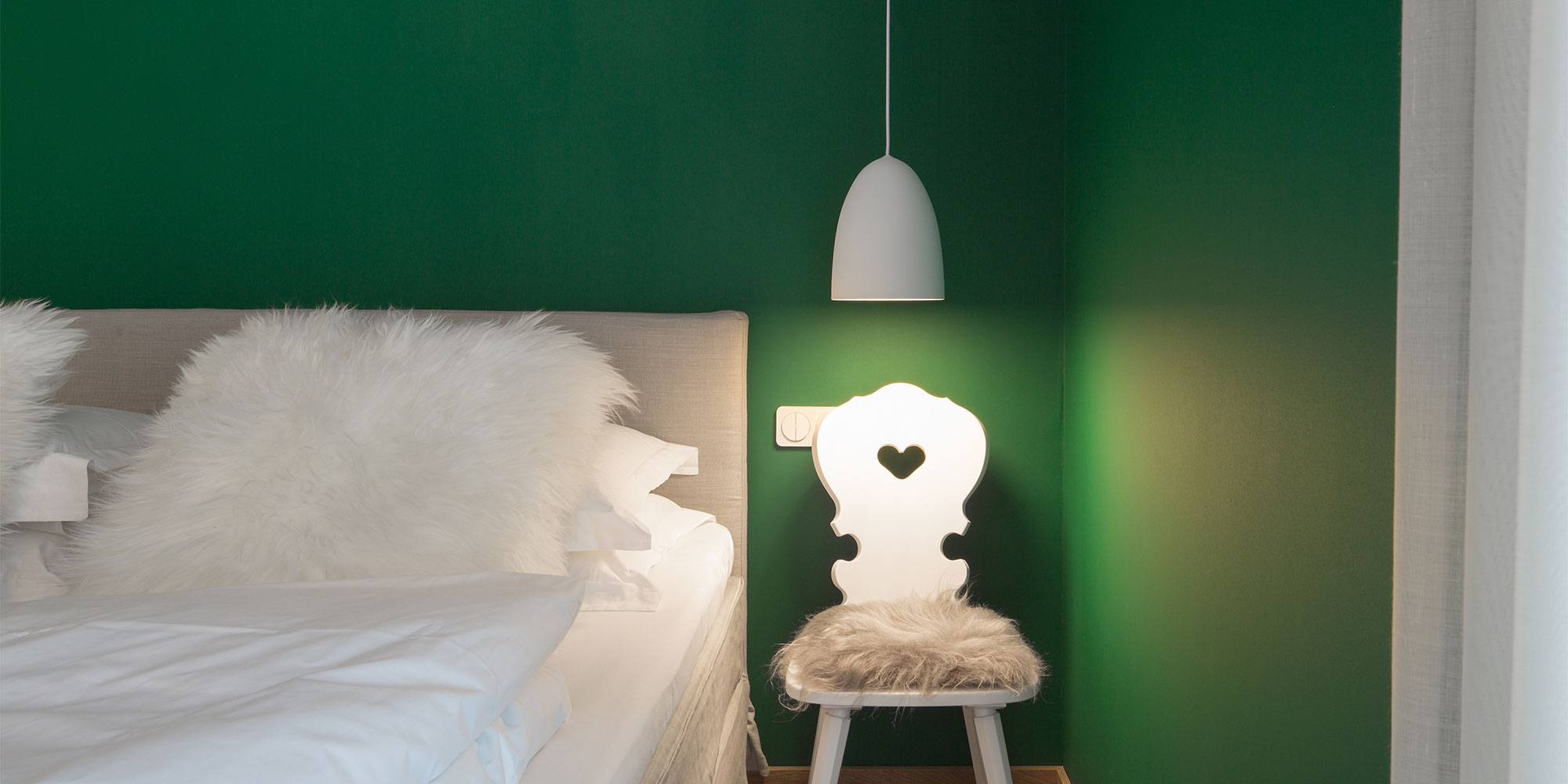 Grünes Schlafzimmer mit Nachttischlampe und Bett, gleichmäßige Wandfläche im Hintergrund