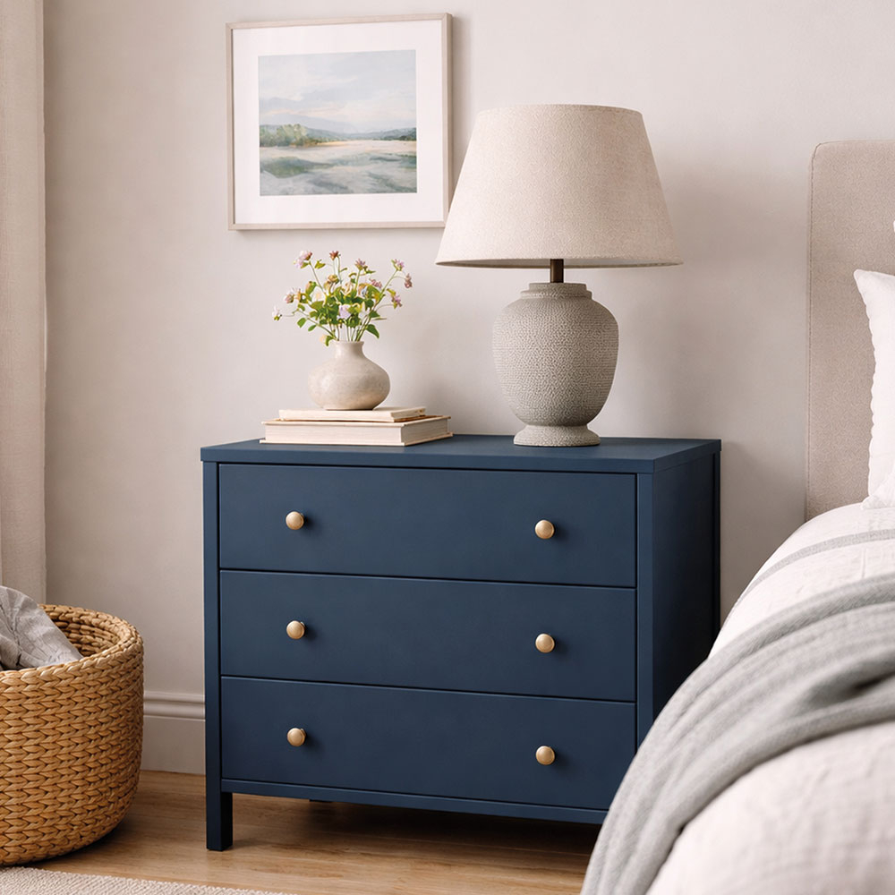Dunkelblau gestrichene Kommode neben dem bett.