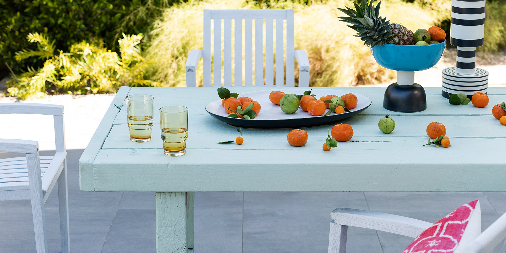 Grünes Metall-Bistroset im Garten mit Blumentöpfen auf dem Tisch