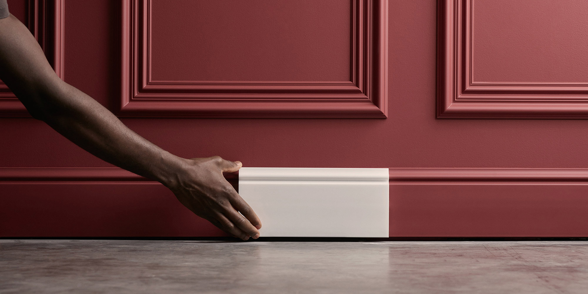 Ein Wohnzimmer mit dekorativen Wandfeldern und klassischen Stuck-Fußleisten in Landhausoptik.