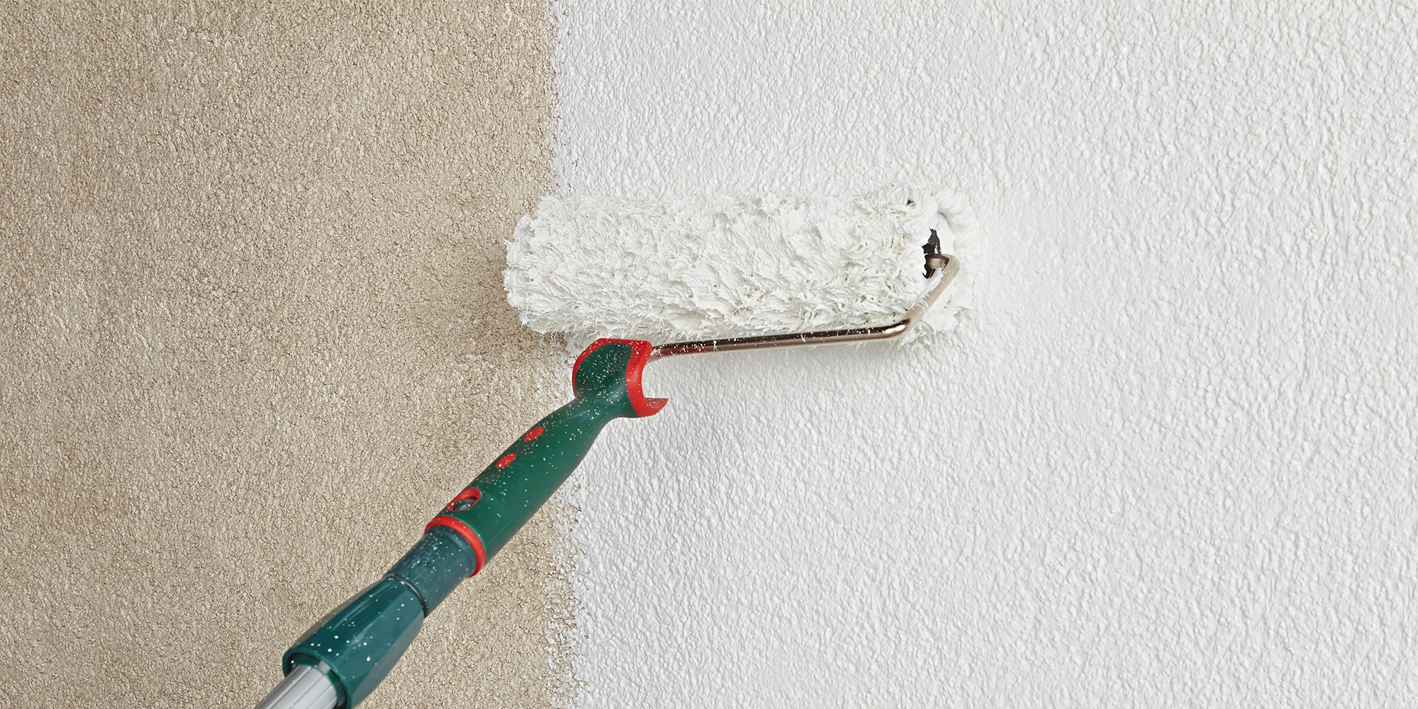 Farbroller beschichtet eine strukturierte Fassade mit weißer Farbe