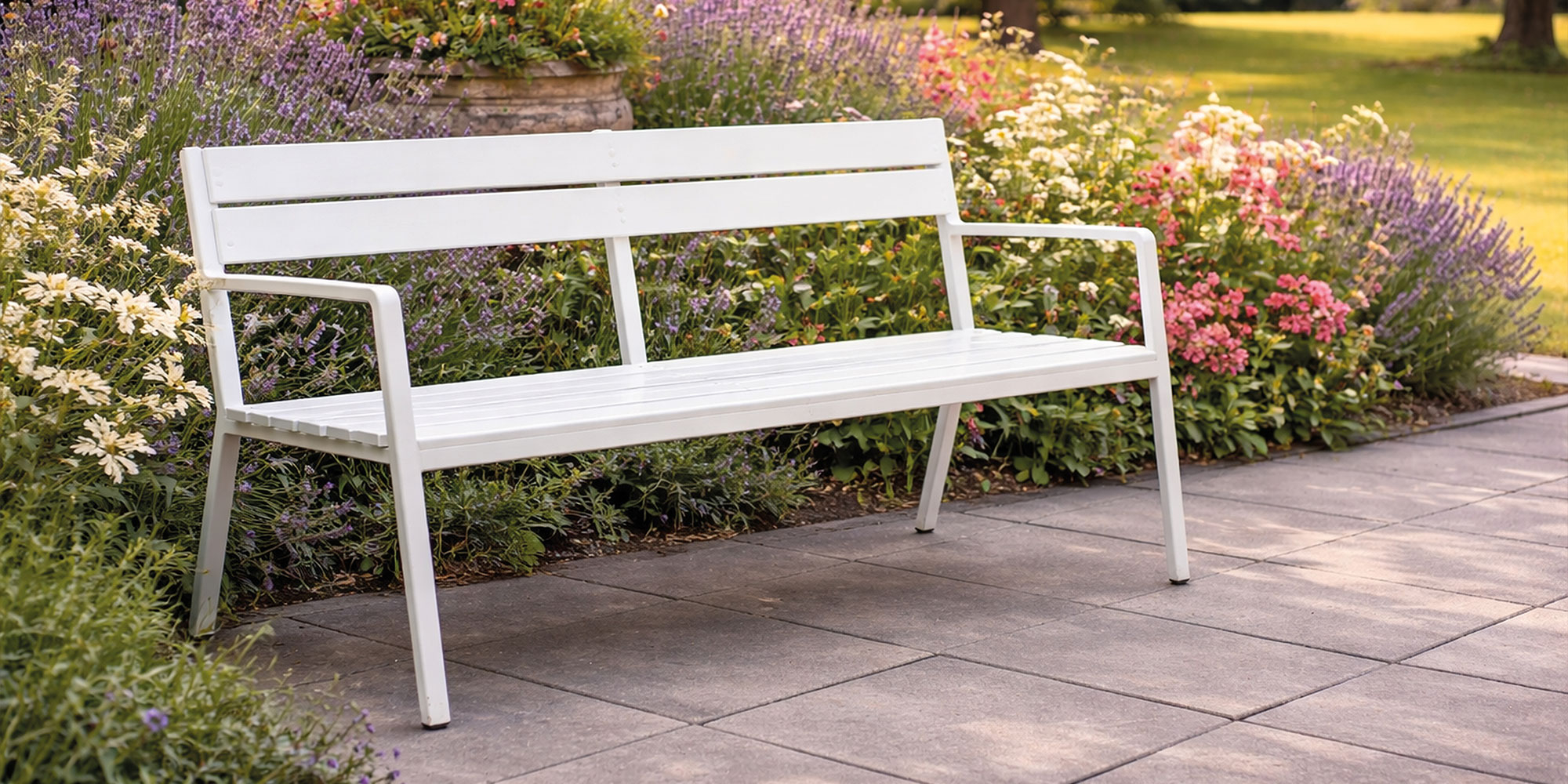 Weiß lackierte Gartenbank vor Lavendel auf Steinweg im Garten