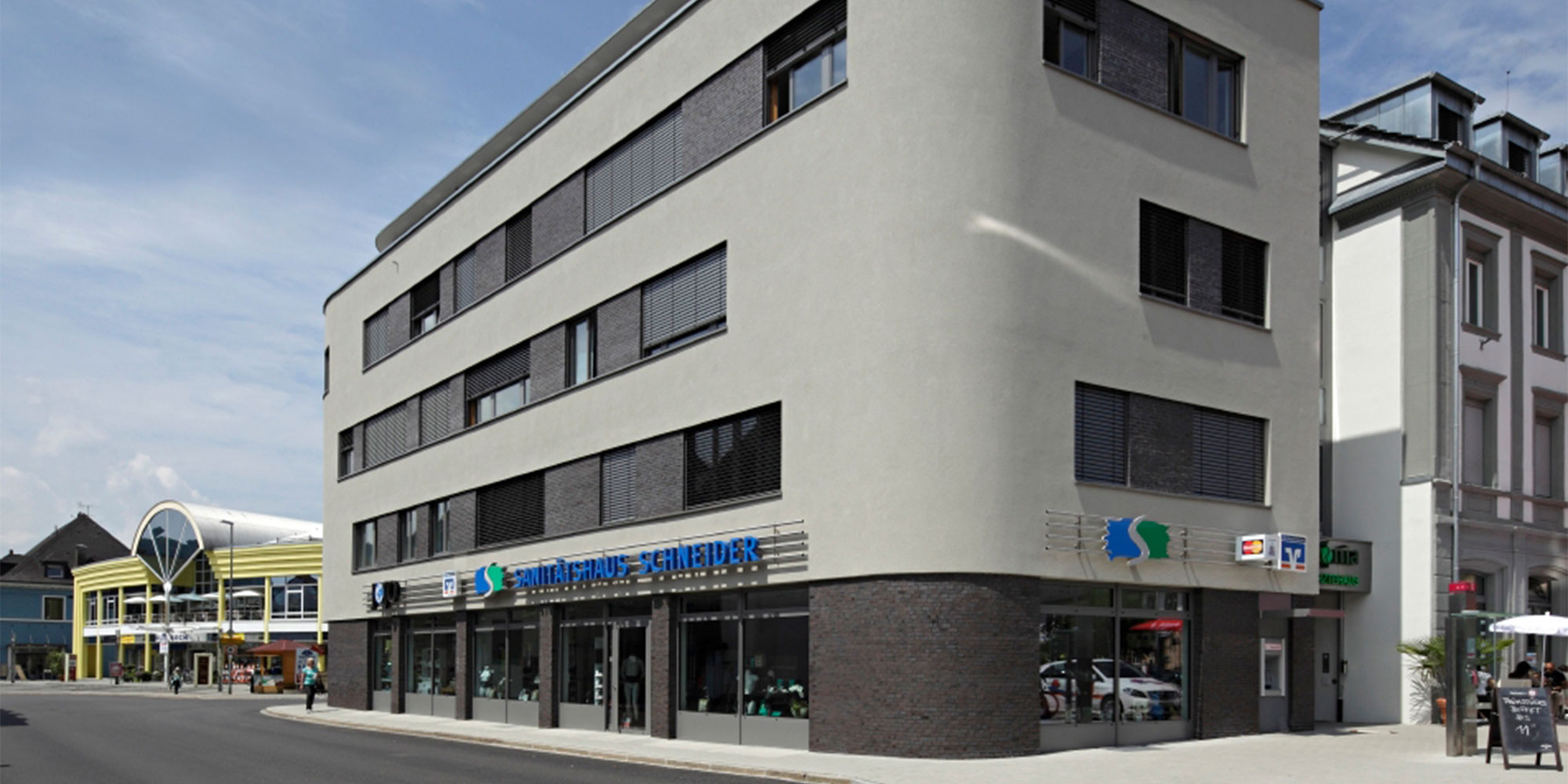 Großes Gebäude mit heller Putzfassade Straßenansicht mit Schaufenstern im Erdgeschoss