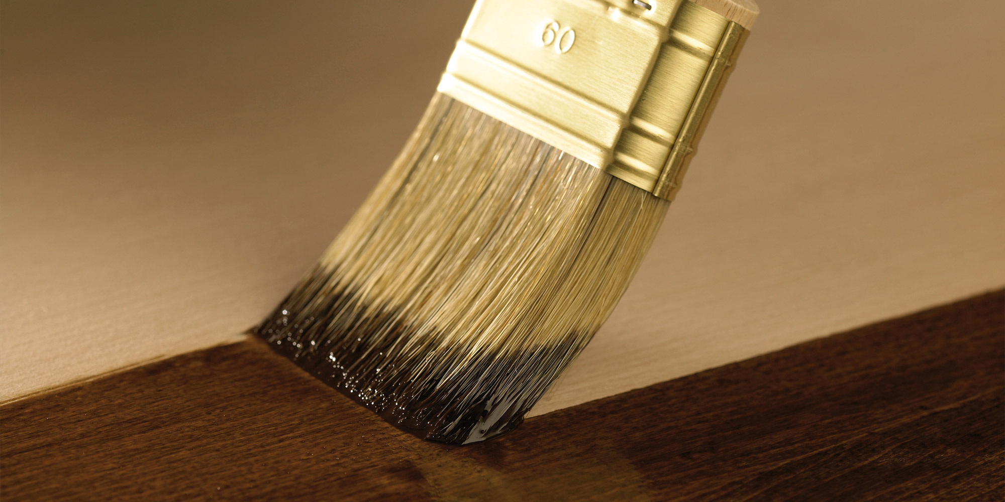 Pinsel traegt Lasur auf Holz auf