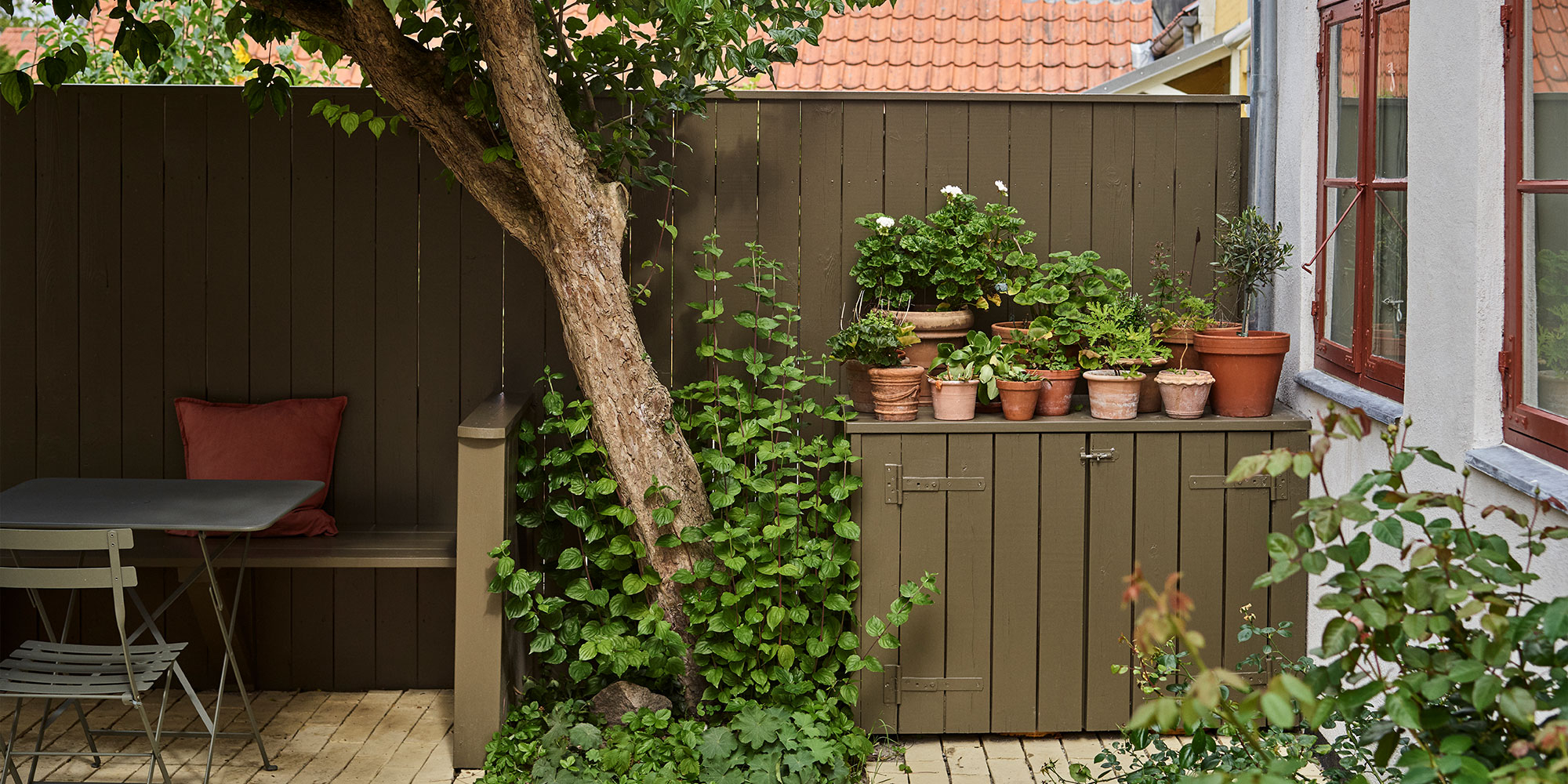 Garten-Sitzecke mit gestrichenem Holzzaun und Schrank, bepflanzt - Inspiration für Außenlacke