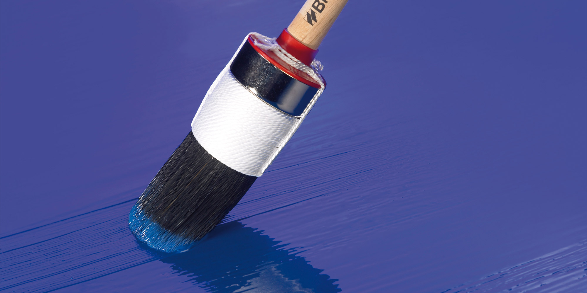 Pinsel streicht blauen Lack auf glatte Oberfläche