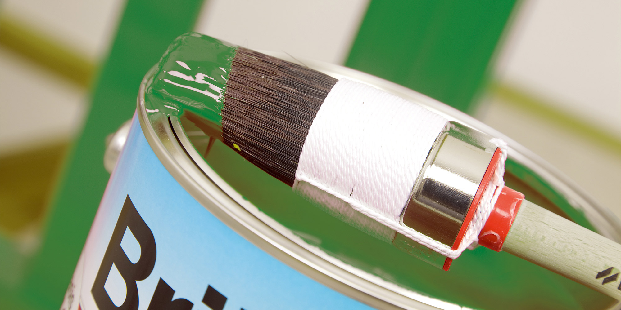 Pinsel mit grüner Farbe auf dem Lacktopf für Verdünnung und Verarbeitung im Außenbereich