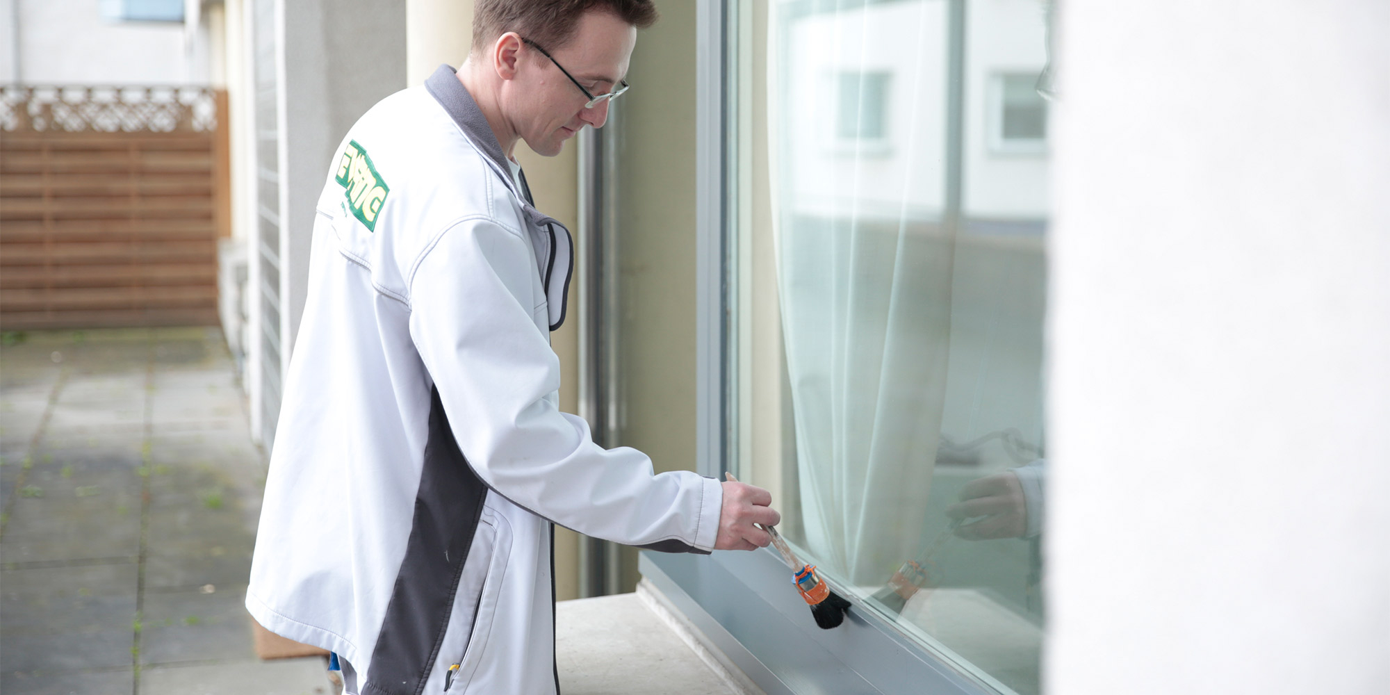 Handwerker streicht die Fensterbank mit Pinsel an einem großen Fenster