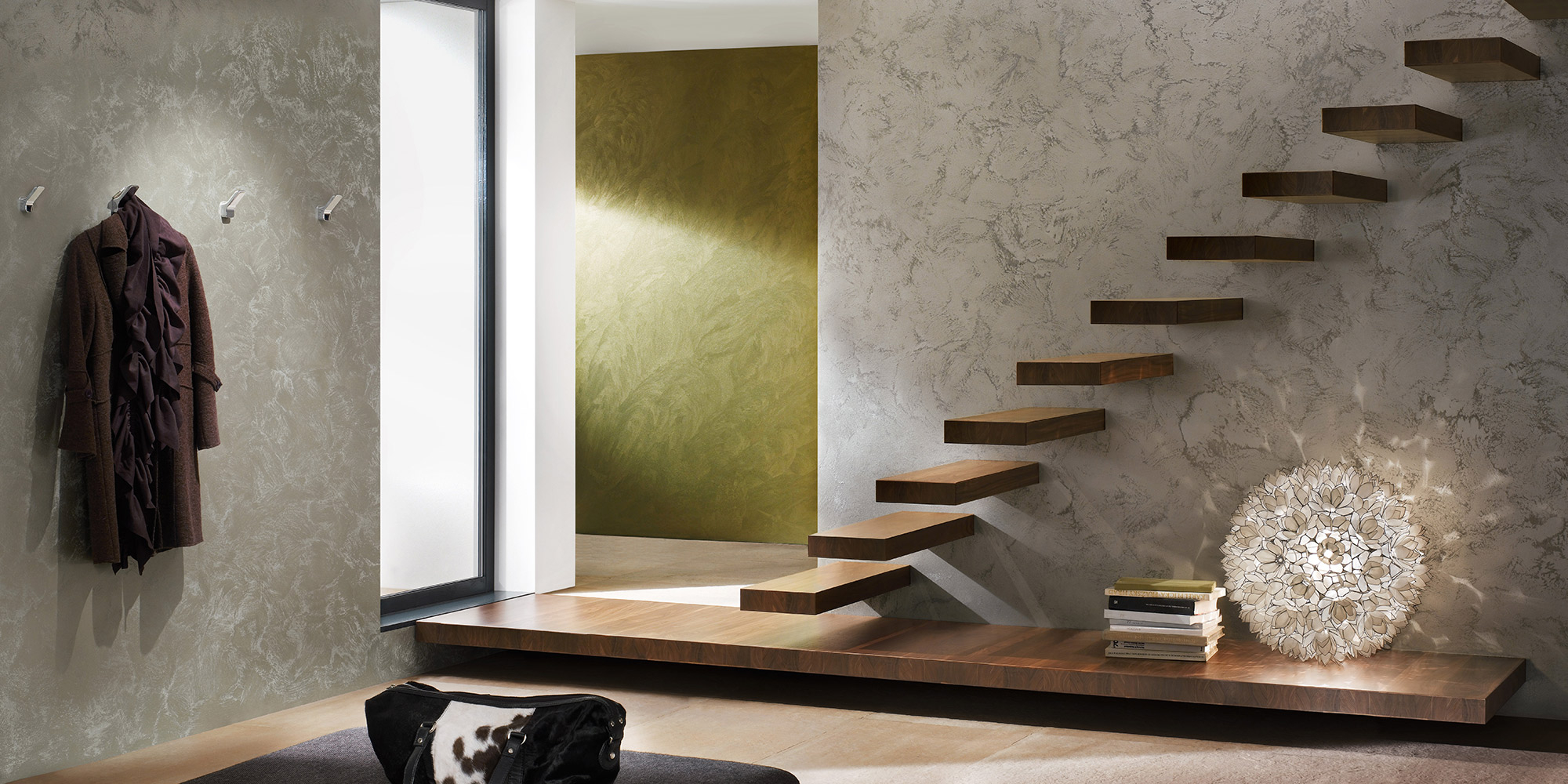 Modernes Raumdesign mit schwebender Holztreppe, Strukturwand, Garderobe und dekorativer Leuchte