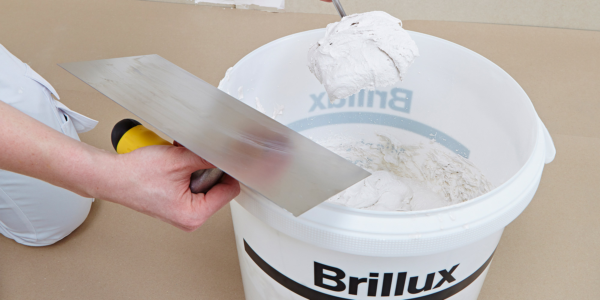 Spachtelmasse wird im Eimer mit Kelle angerührt, Vorbereitung für das Glätten von Flächen