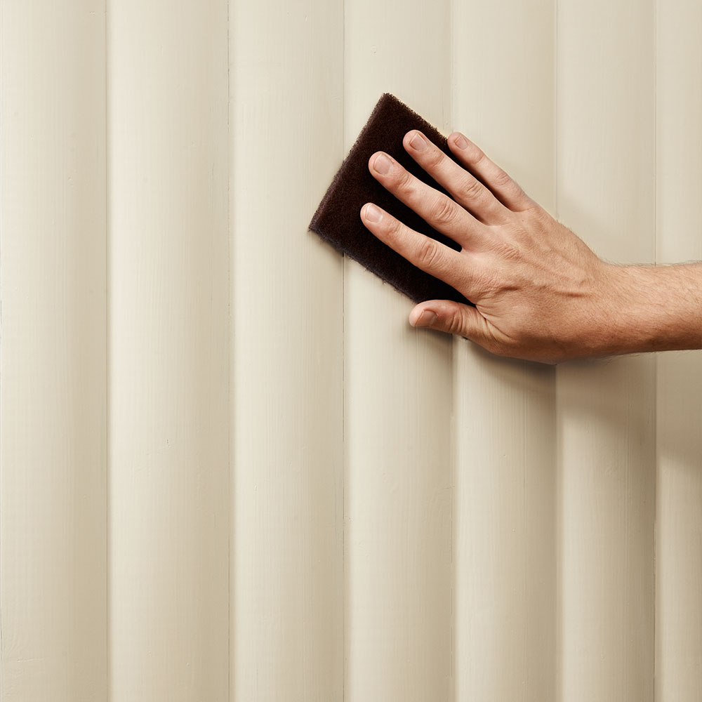 Hand schleift hell lasiertes Holzpaneel mit Schleifvlies, Vorbereitung fuer eine gleichmaessige Aufhellung