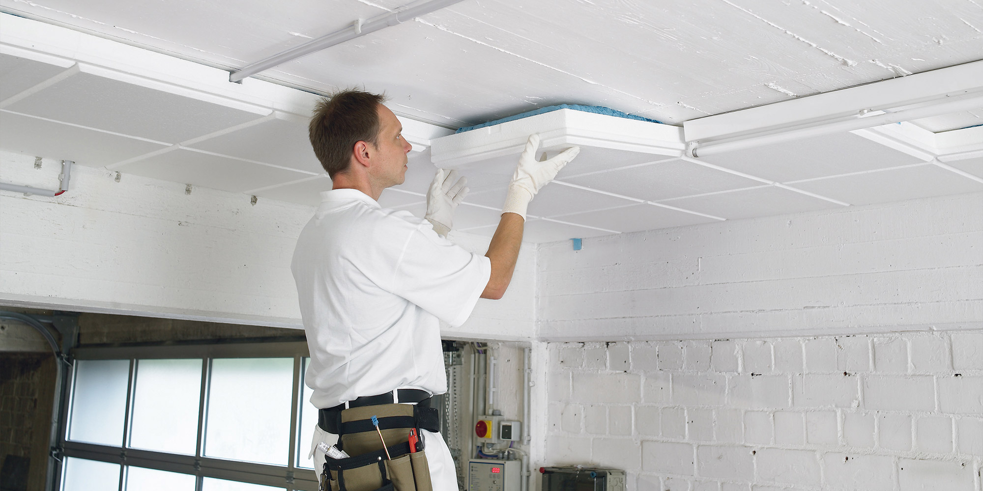 Handwerker montiert Dämmplatten an der Decke für Wärmedämmung