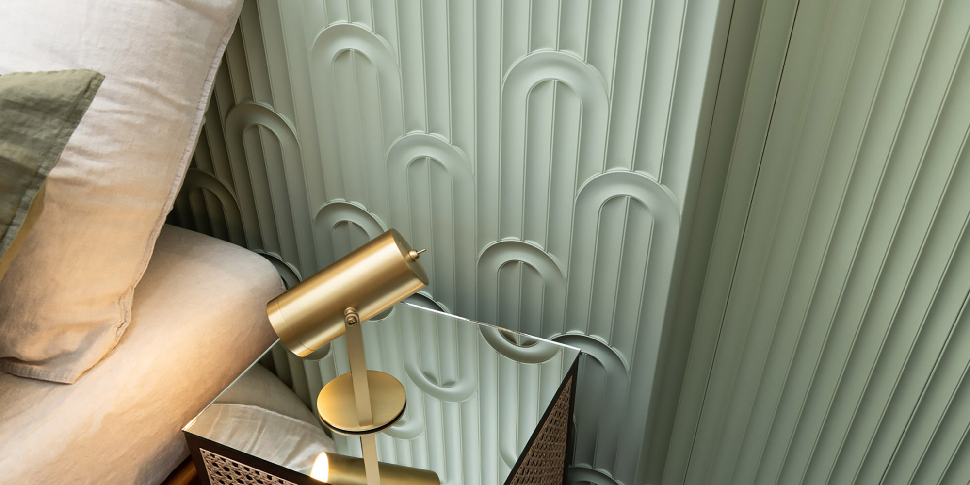 Schlafzimmer mit Wandpaneelen aus Stuck in dekorativem Retrodesign mit Bögen in Salbeigrün.