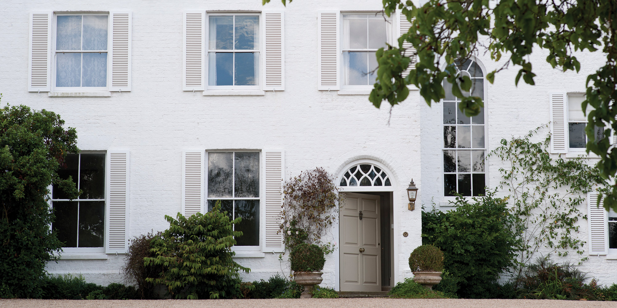 Weisse Klinkerfassade eines Hauses mit Fenstern und Eingang als Beispiel fuer Klinker Untergrund