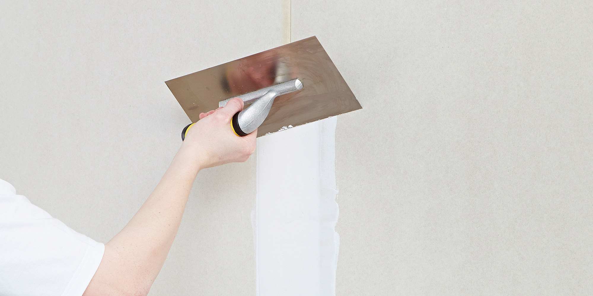 Spachtel wird mit einer Glattkelle auf eine Innenwand aufgetragen