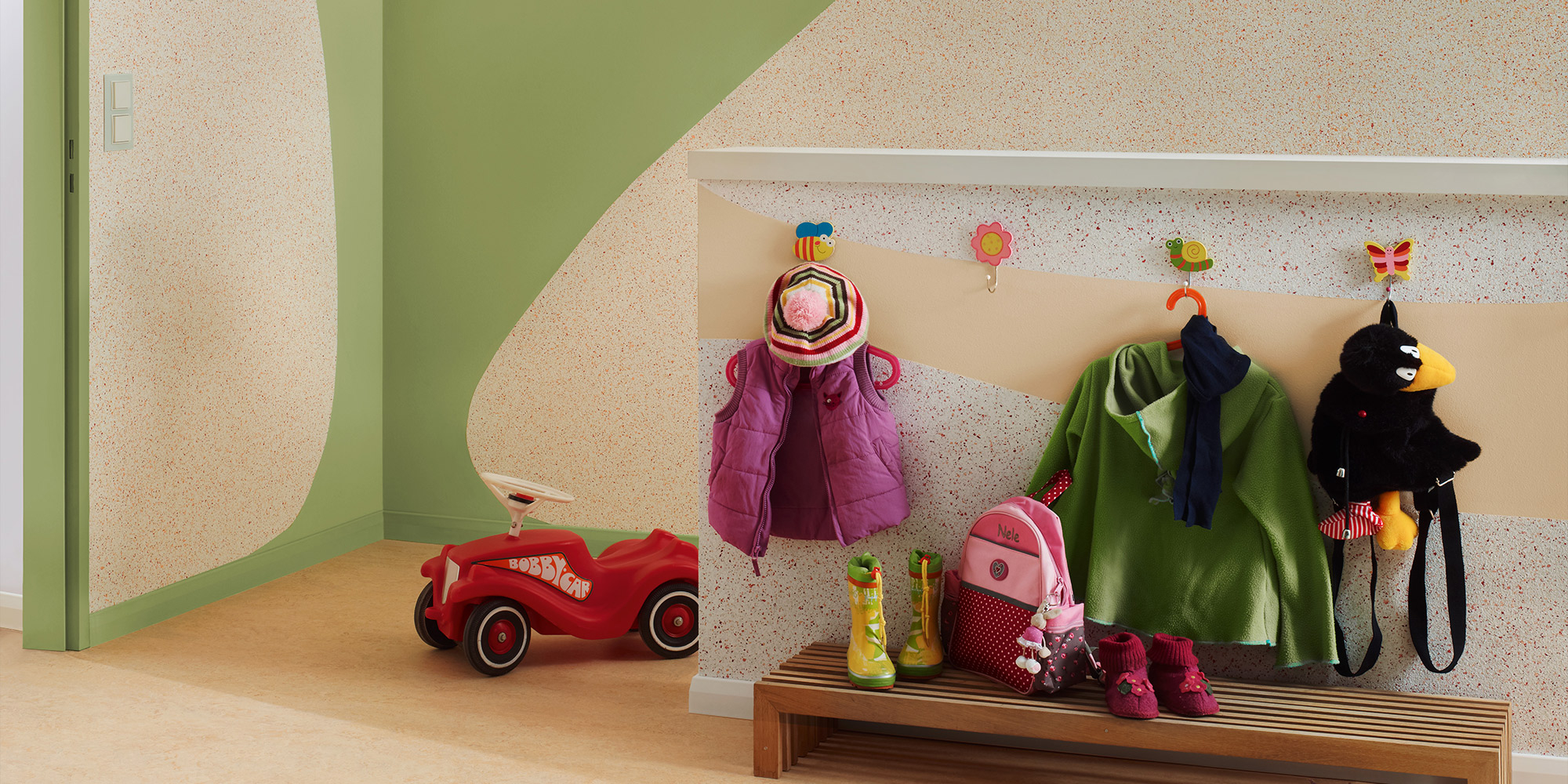 Flur mit strukturierter, gesprenkelter Wand, grüner Akzentfläche und Kinder-Garderobe